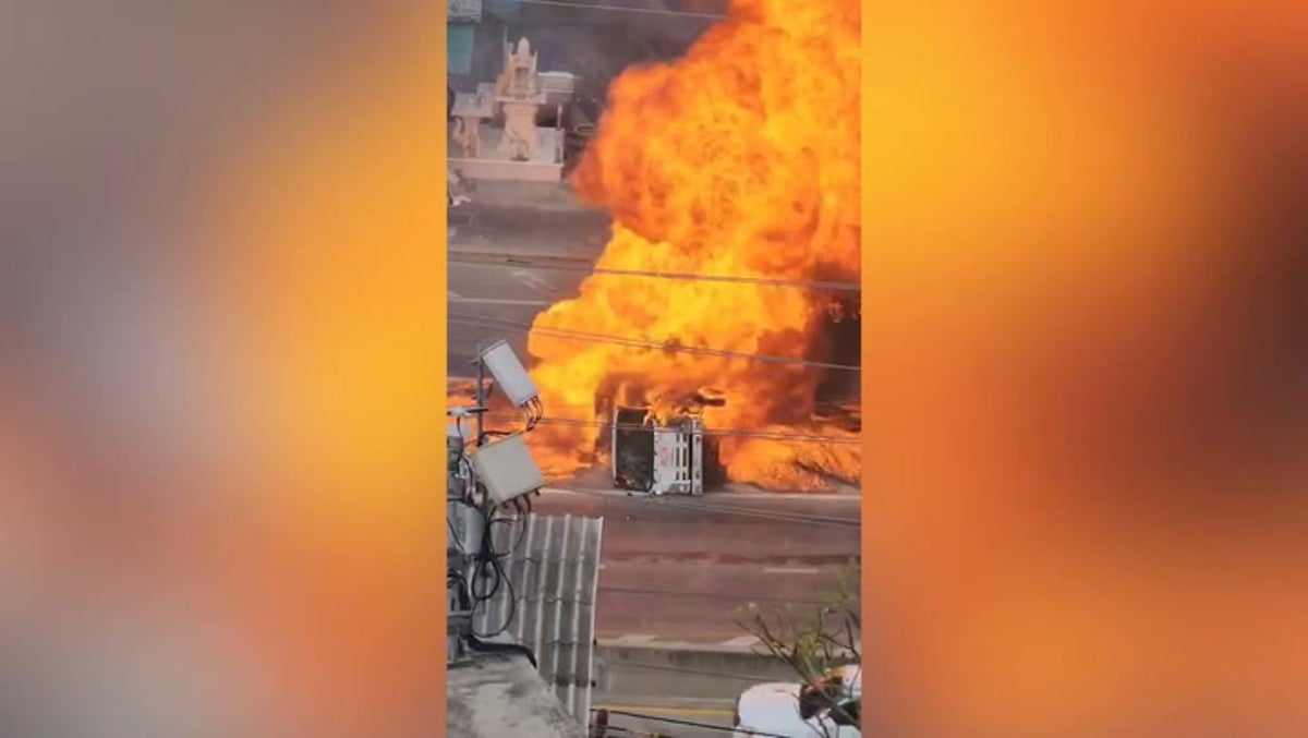 Flames engulf overturned fuel truck in middle of road as explosion injures two