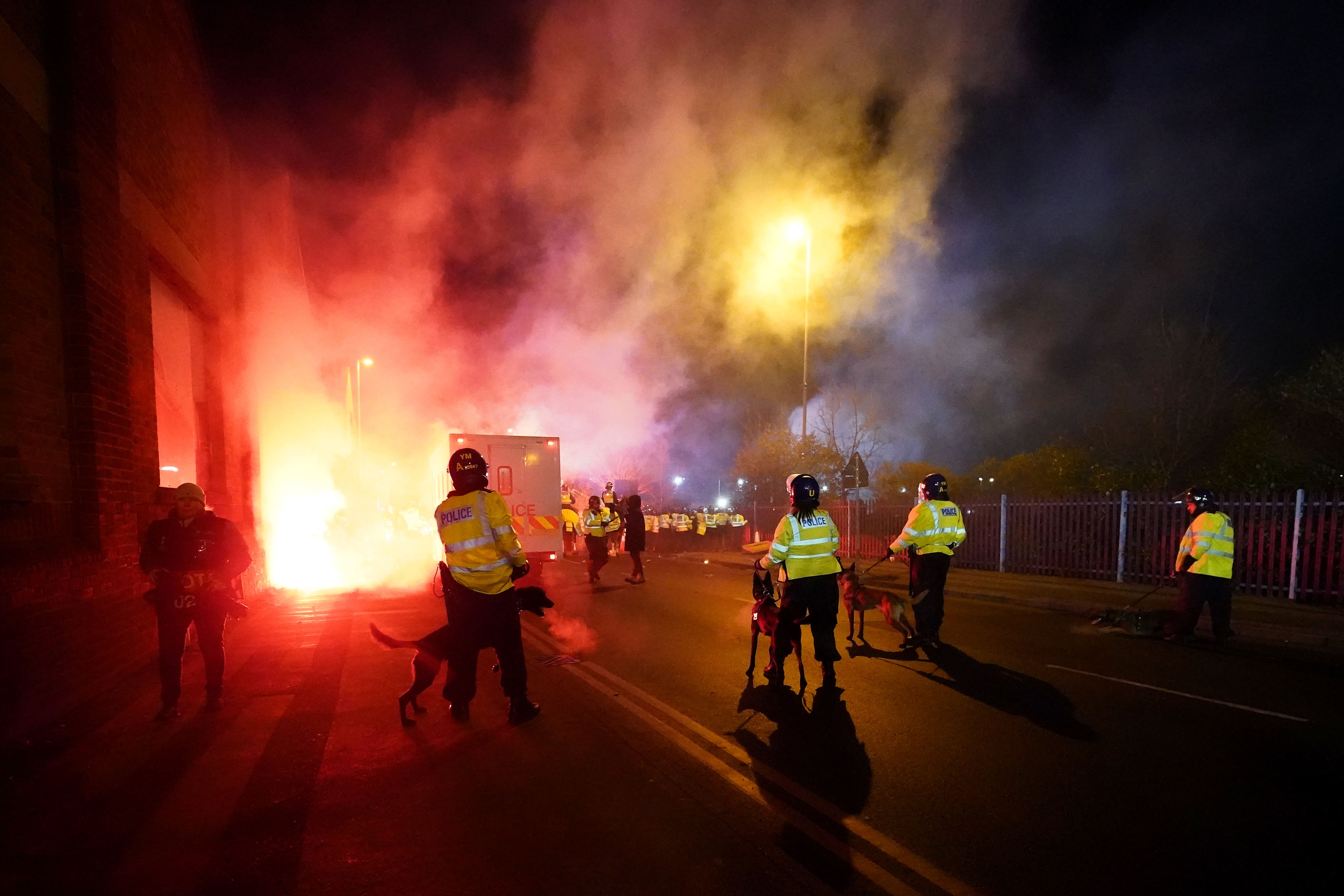 Police attempt to put out flares that have thrown towards them outside the stadium