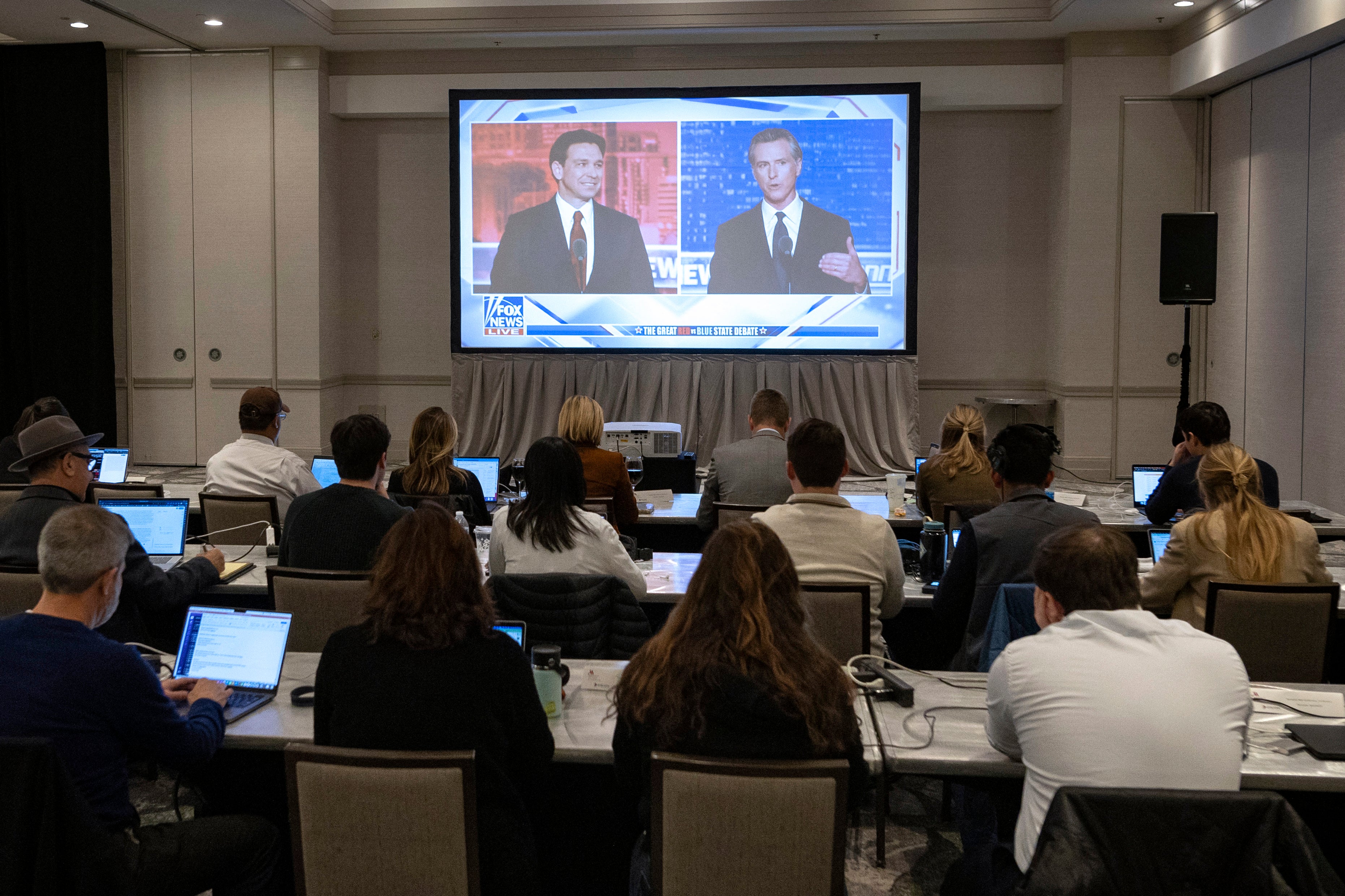 Florida Governor and Republican presidential hopeful Ron DeSantis (L) and California Governor Gavin Newsom (R) appear on screen from the press room during a debate held by Fox News, in Alpharetta, Georgia, on November 30, 2023