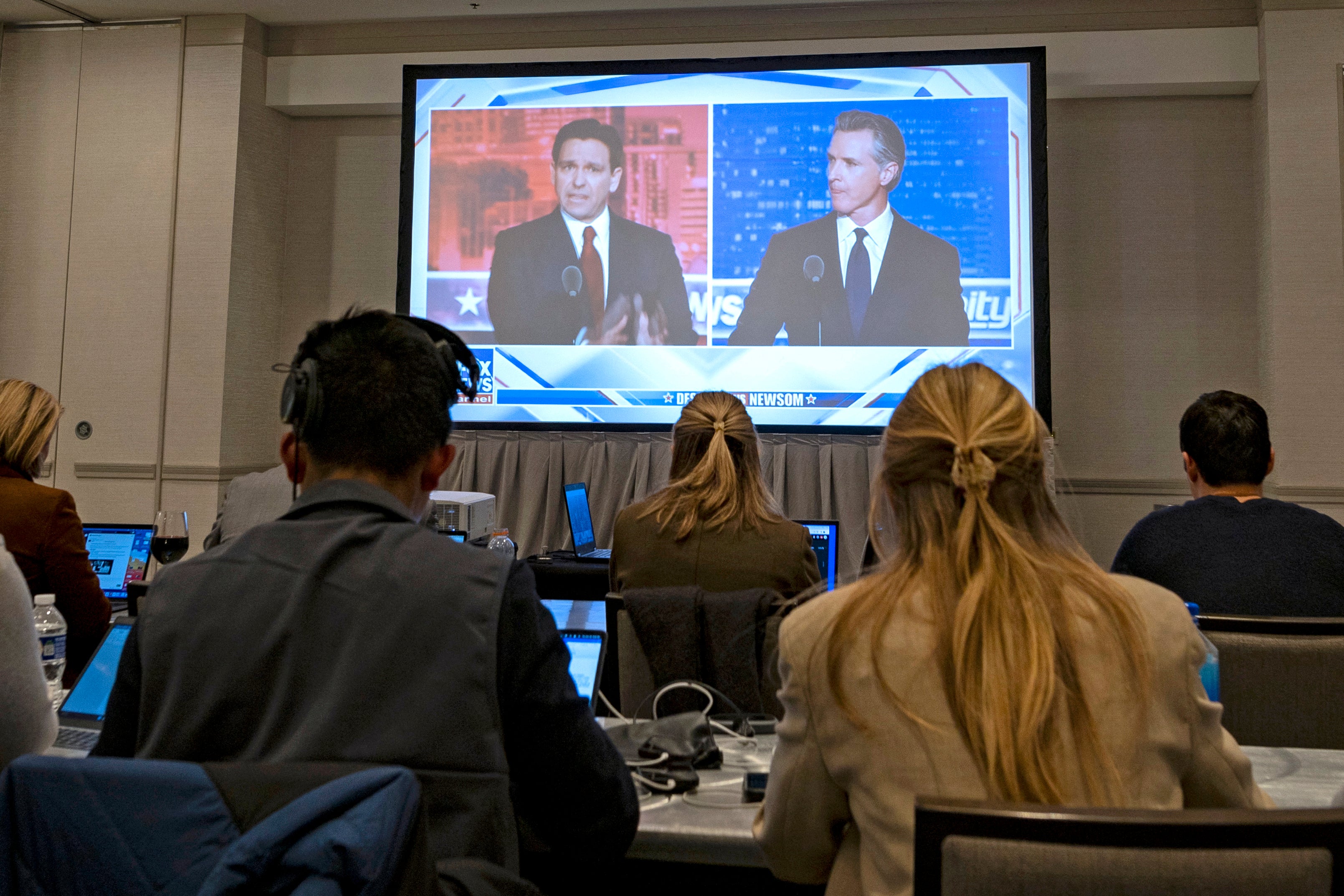 Florida Governor and Republican presidential hopeful Ron DeSantis (L) and California Governor Gavin Newsom (R) appear on screen from the press room during a debate held by Fox News, in Alpharetta, Georgia, on November 30, 2023