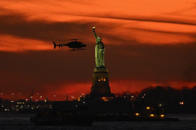 <p>A helicopter flies past the Statue of Liberty at sunset in New York. </p>