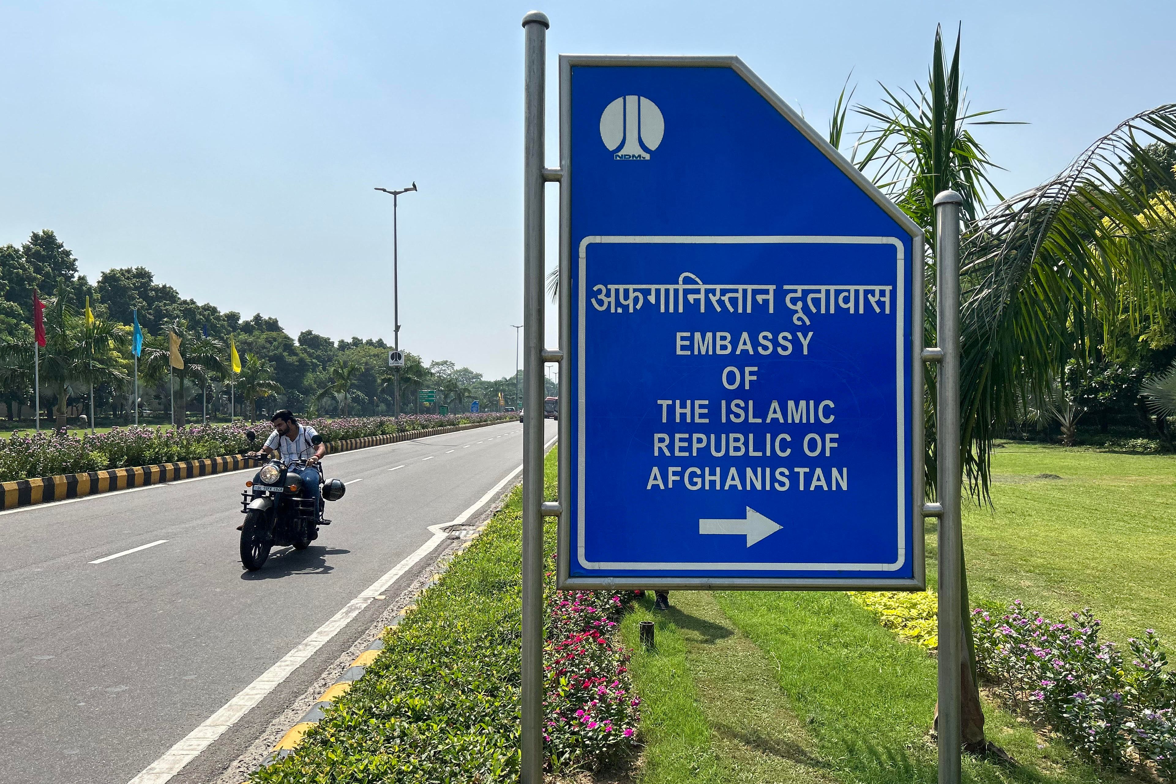 A motorist rides past a sign board for the embassy of the Islamic Republic of Afghanistan in New Delhi