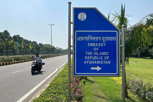 <p>A motorist rides past a sign board for the embassy of the Islamic Republic of Afghanistan in New Delhi</p>