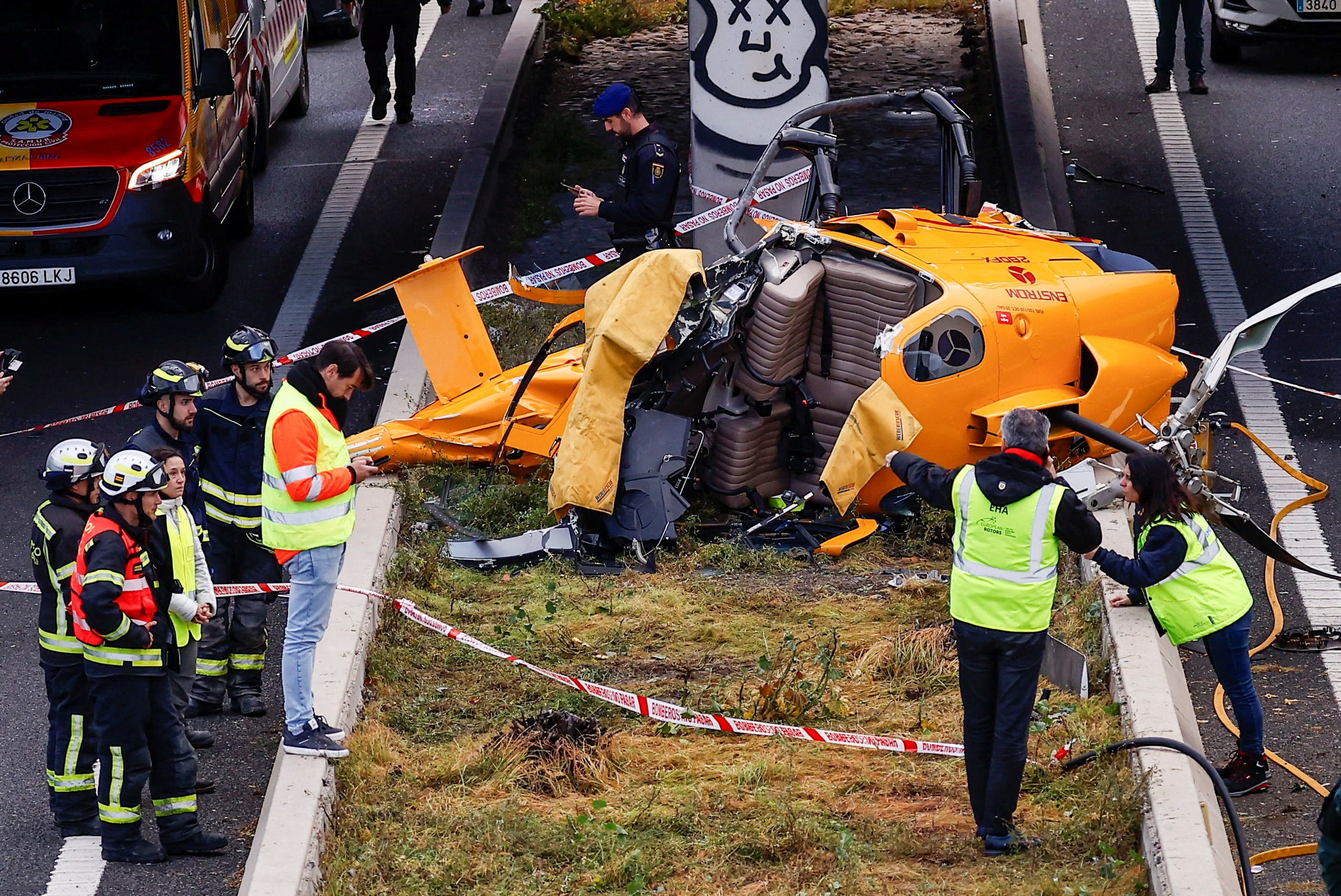 Eight emergency services officials stand next to the wreckage strewn across the Spanish motorway