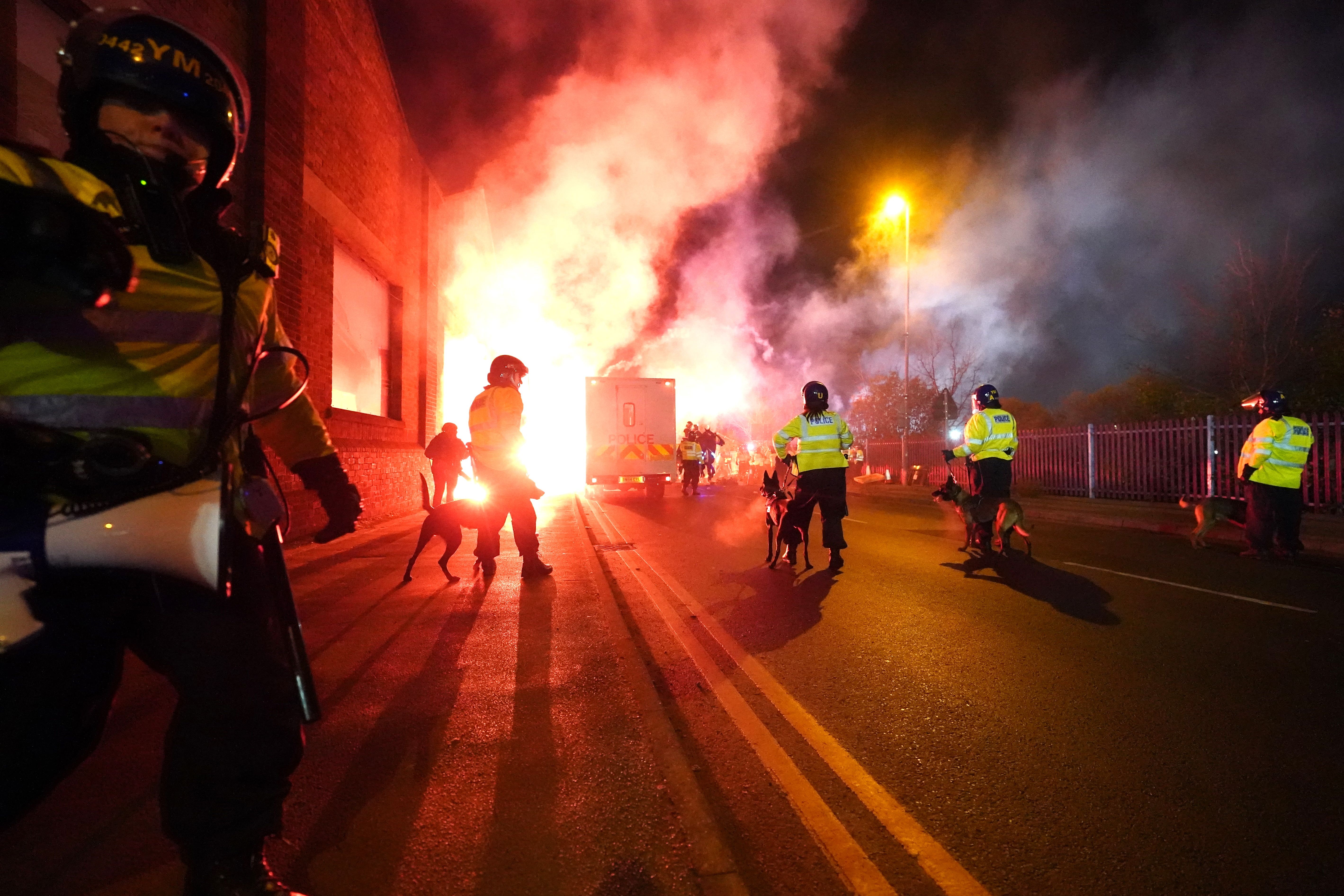 Police officers with dogs as flares are set off outside the stadium (David Davies/PA)