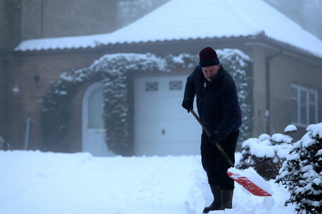 <p>A man clears snow from his driveway, Keele, Staffordshire, Britain</p>