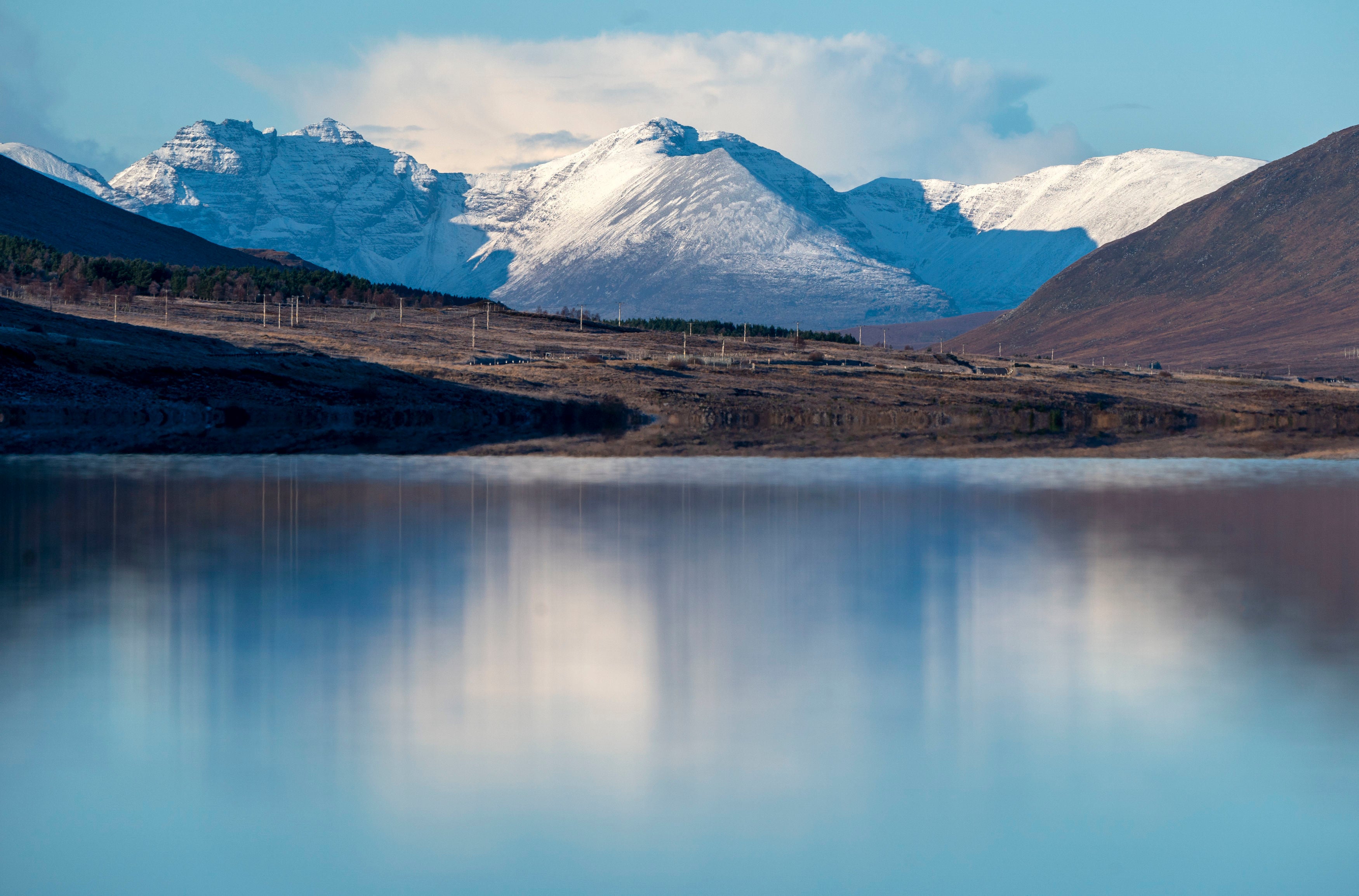 The snow-covered peak of Beinn Eighe and the mountains of Torridon reflected in Loch Glascarnoch near Ullapool, Wester Ross