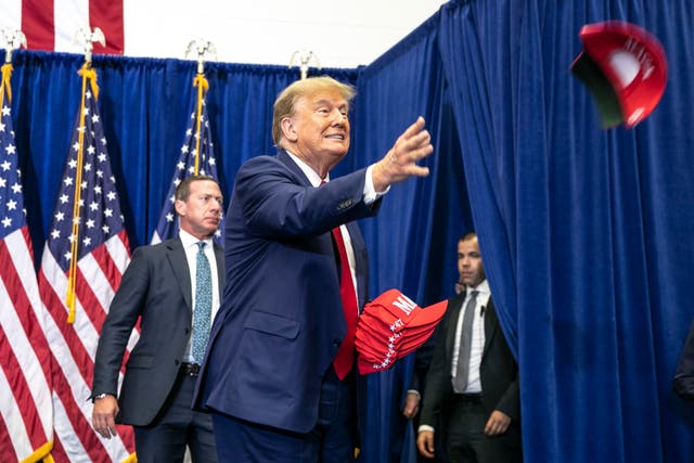 <p>Republican presidential candidate and former President Donald Trump tosses out hats to the crowd during a caucus event in Iowa</p>