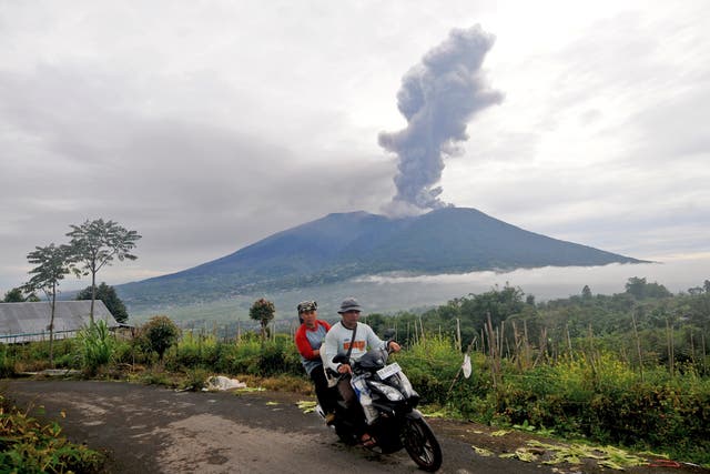 <p>Motorists ride past by as Mount Marapi spews volcanic materials during its eruption in Agam, West Sumatra, Indonesia</p>