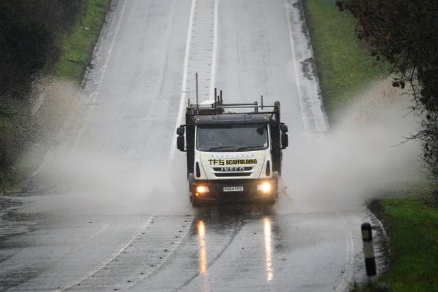 Vehicles driving through service water on a flooded part of the A37 near Bristol (PA)