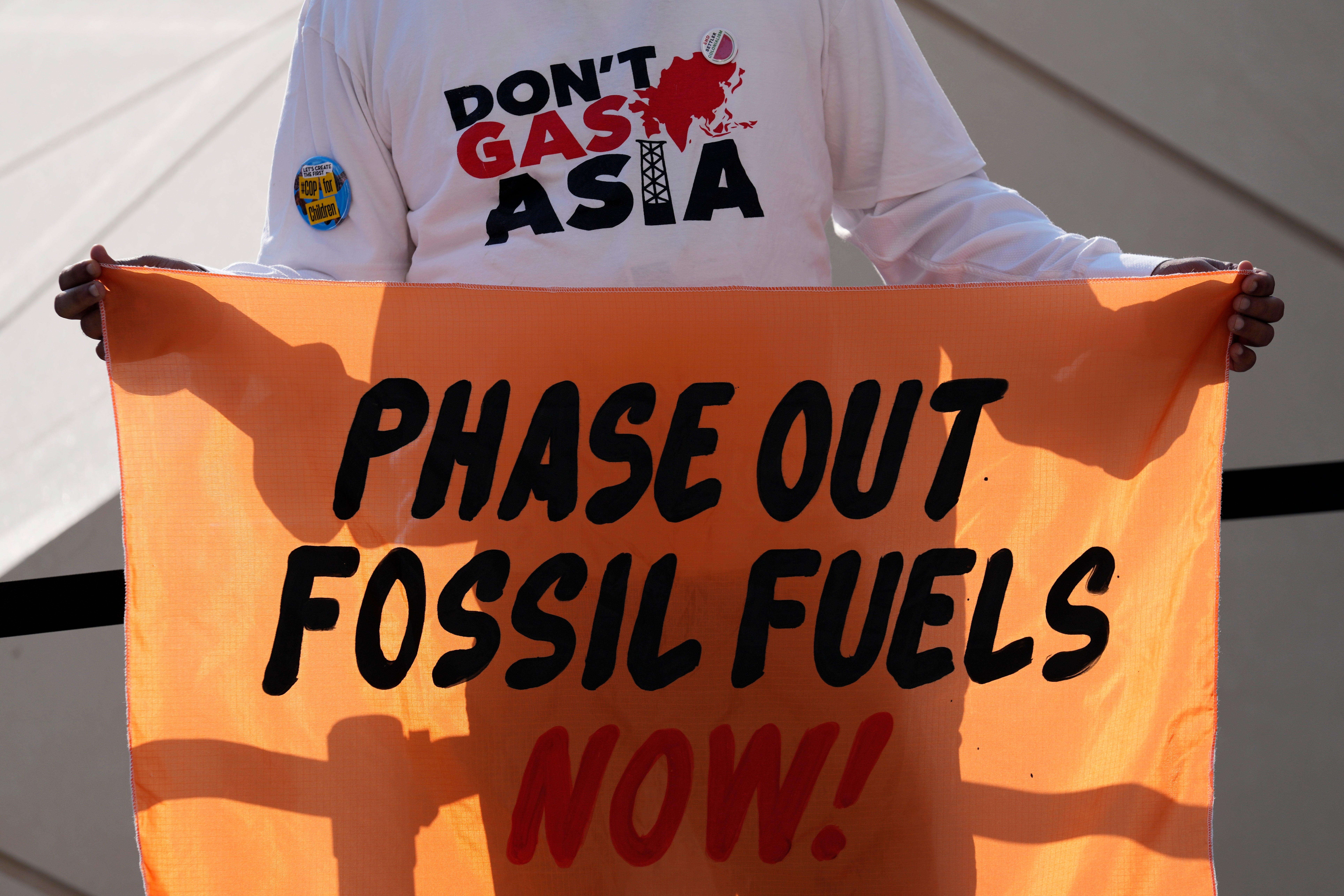 A person holds a sign reading ‘Phase out fossil fuels now!’ during a demonstration for a just and equitable transition from fossil fuels at Cop28