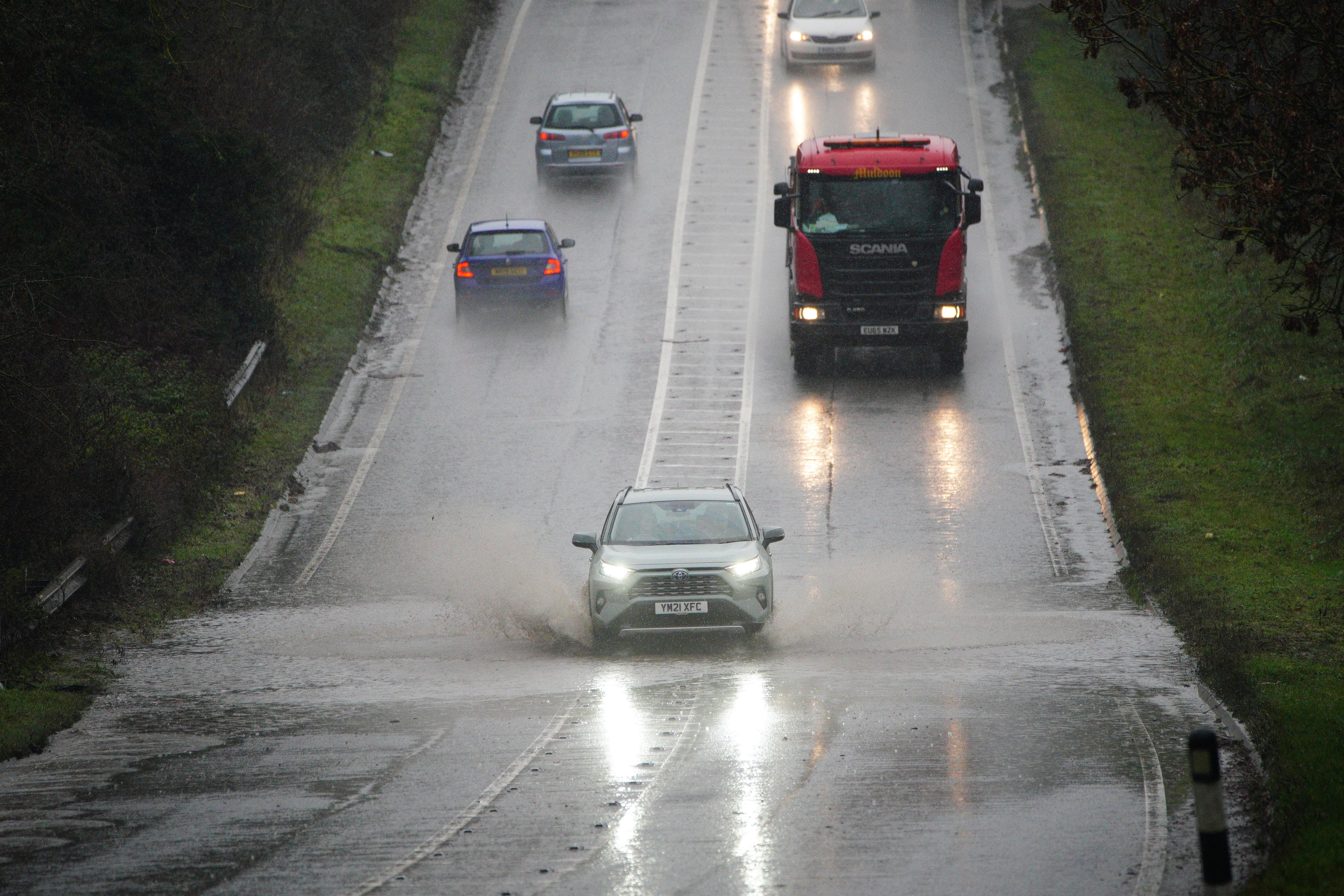 Vehicles driving through service water on a flooded part of the A37 near Bristo (Ben Birchall/PA)