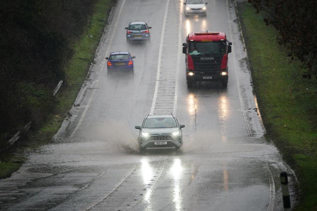 Vehicles driving through service water on a flooded part of the A37 near Bristo (Ben Birchall/PA)