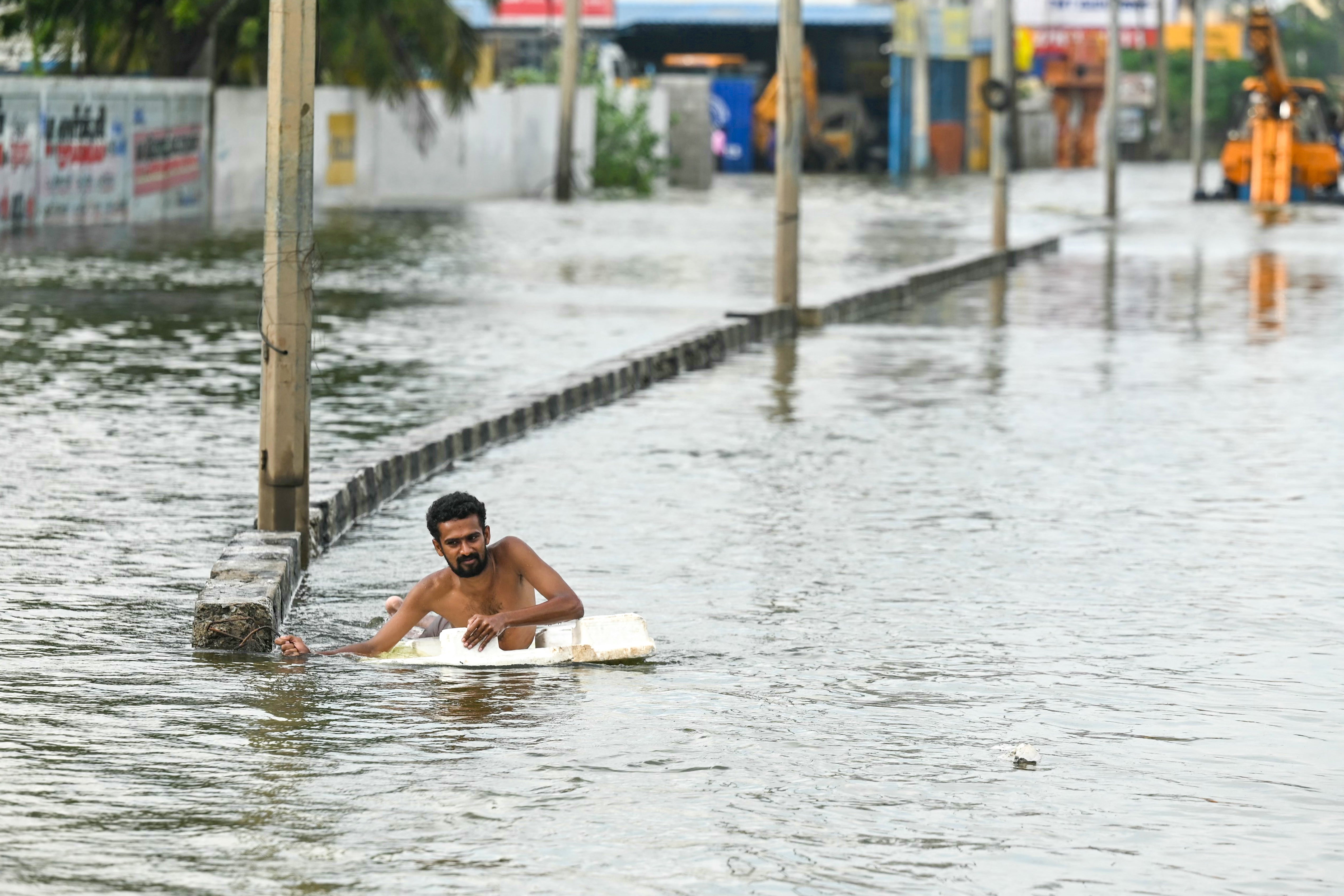 A man wades across a flooded street after heavy rains in Chennai
