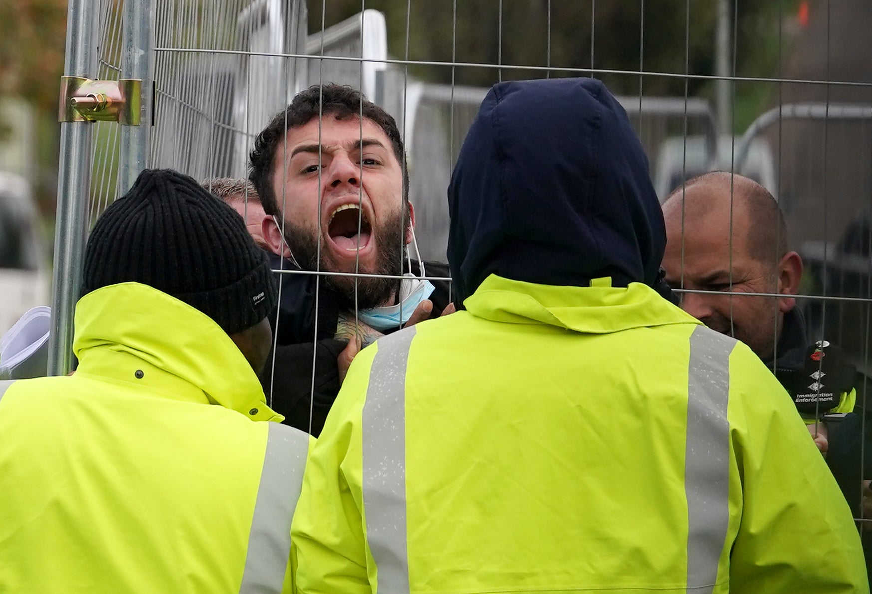 A Manston migrant attempting to communicate with journalists is pinned against a fence by members of staff, before being taken out of view