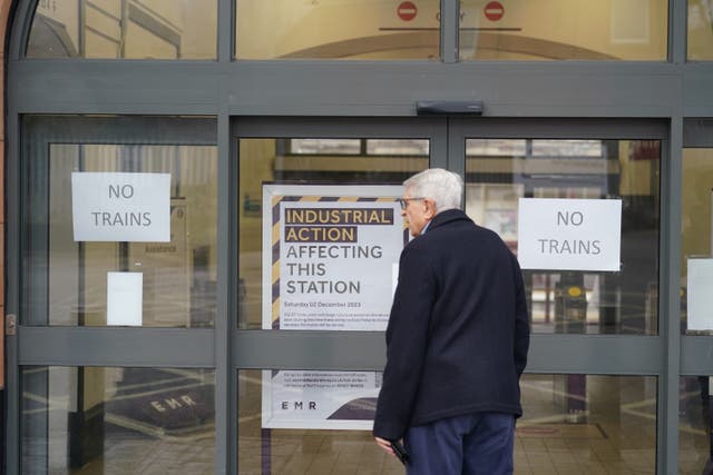 A commuter looks at signs at a closed railway station (PA)