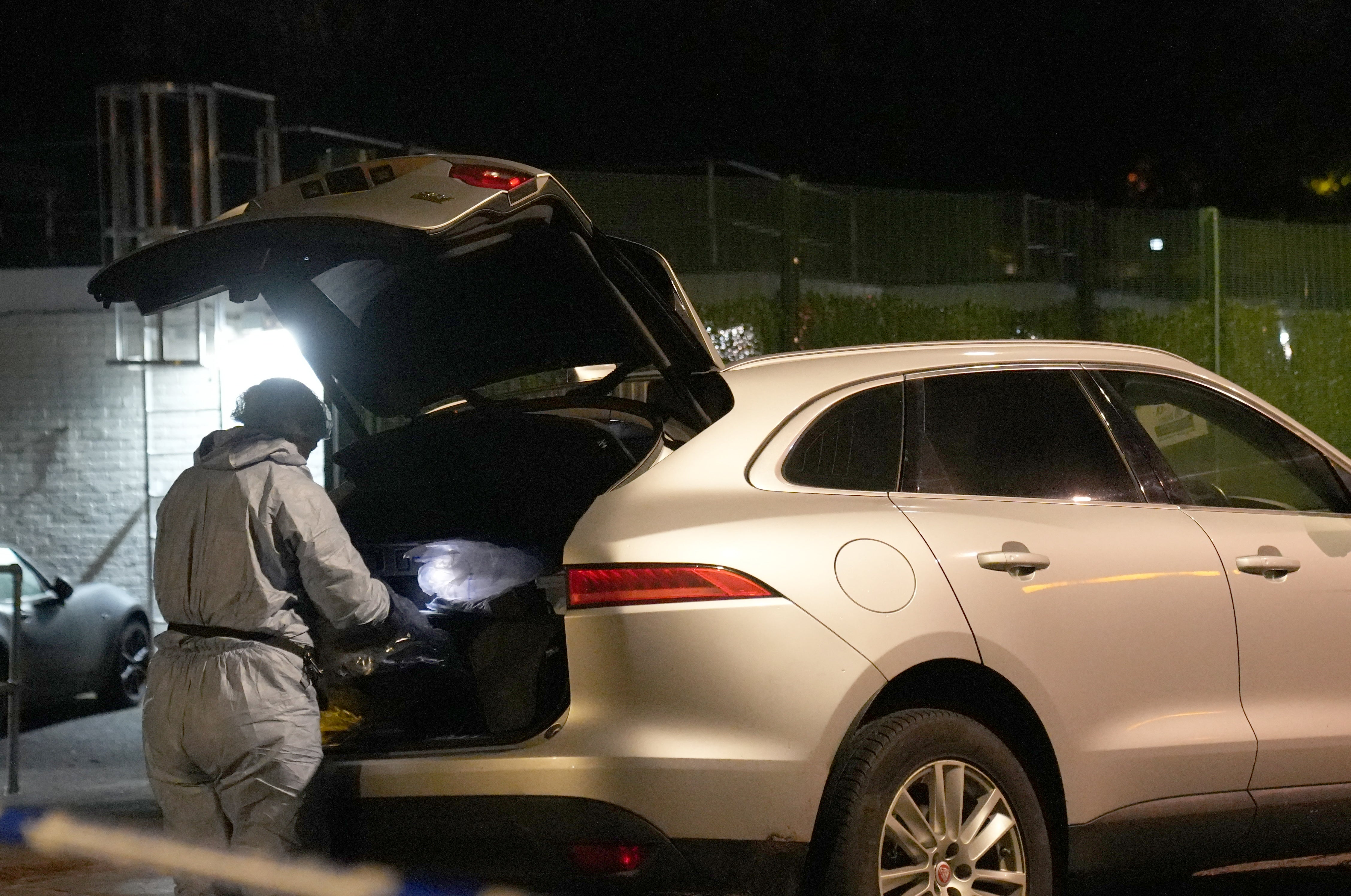 A forensic officer searching a car at the scene near Vine Close, Hackney, east London