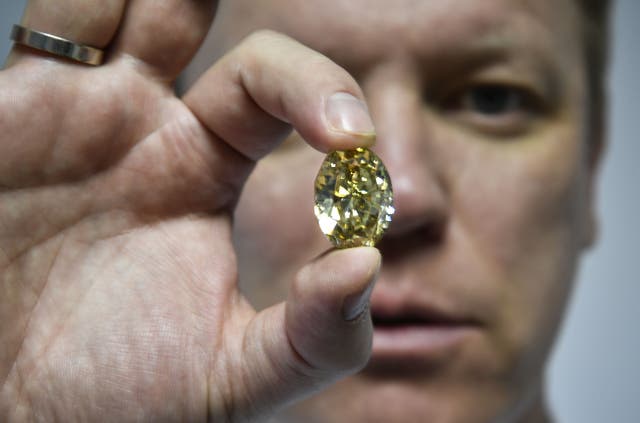 <p>Russian Alrosa Diamond deputy director for sales Yevgeny Tsybukov shows a coloured, fancy brownish greenish yellow oval diamond</p>