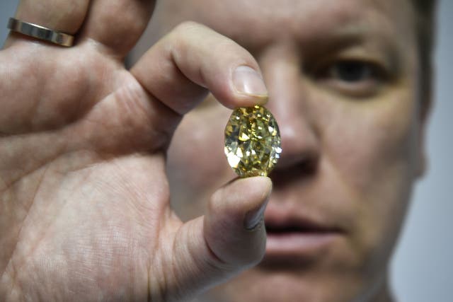 <p>Russian Alrosa Diamond deputy director for sales Yevgeny Tsybukov shows a coloured, fancy brownish greenish yellow oval diamond</p>
