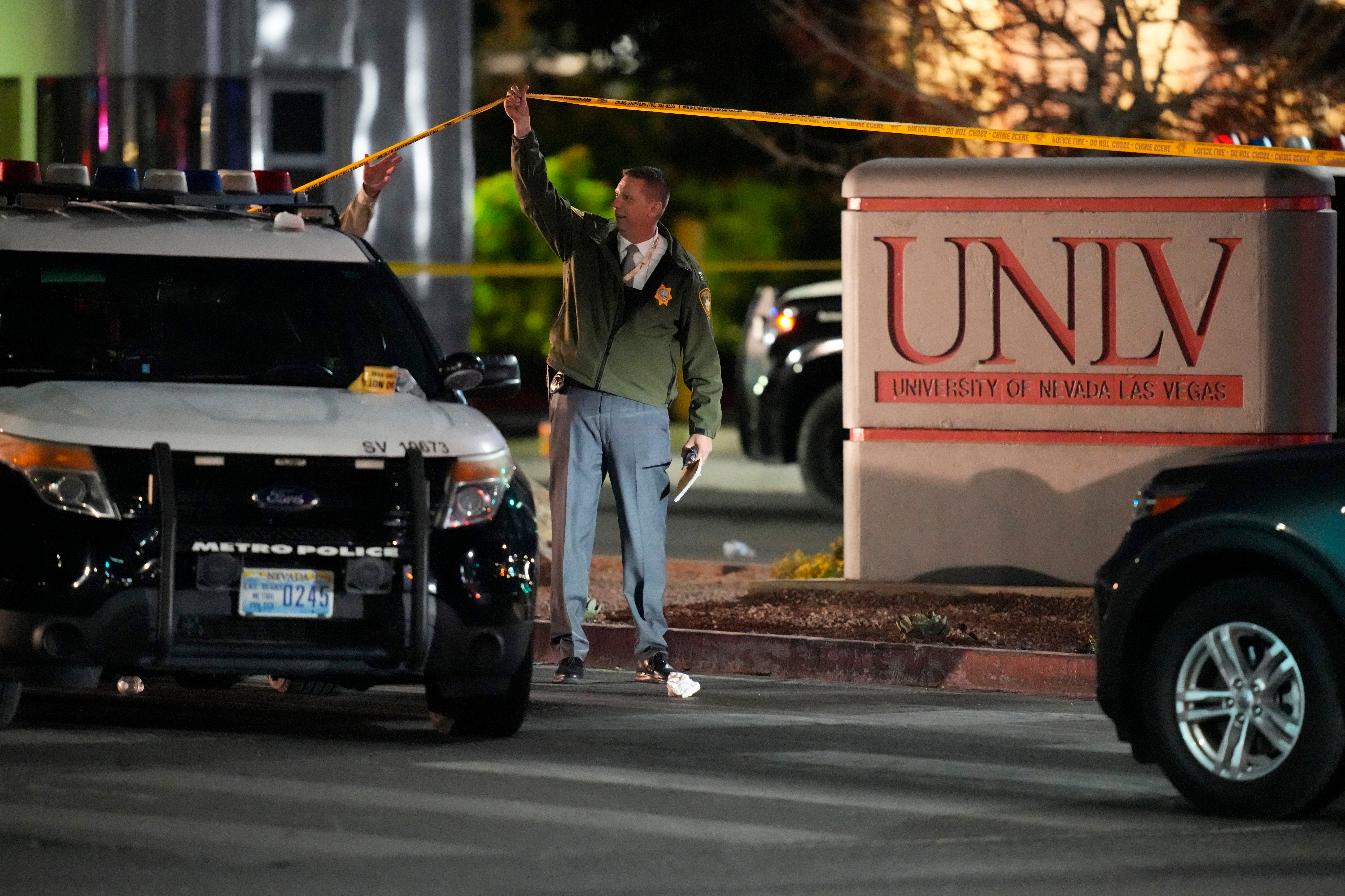 A police officer walks under crime scene tape in the aftermath of a shooting at the University of Nevada