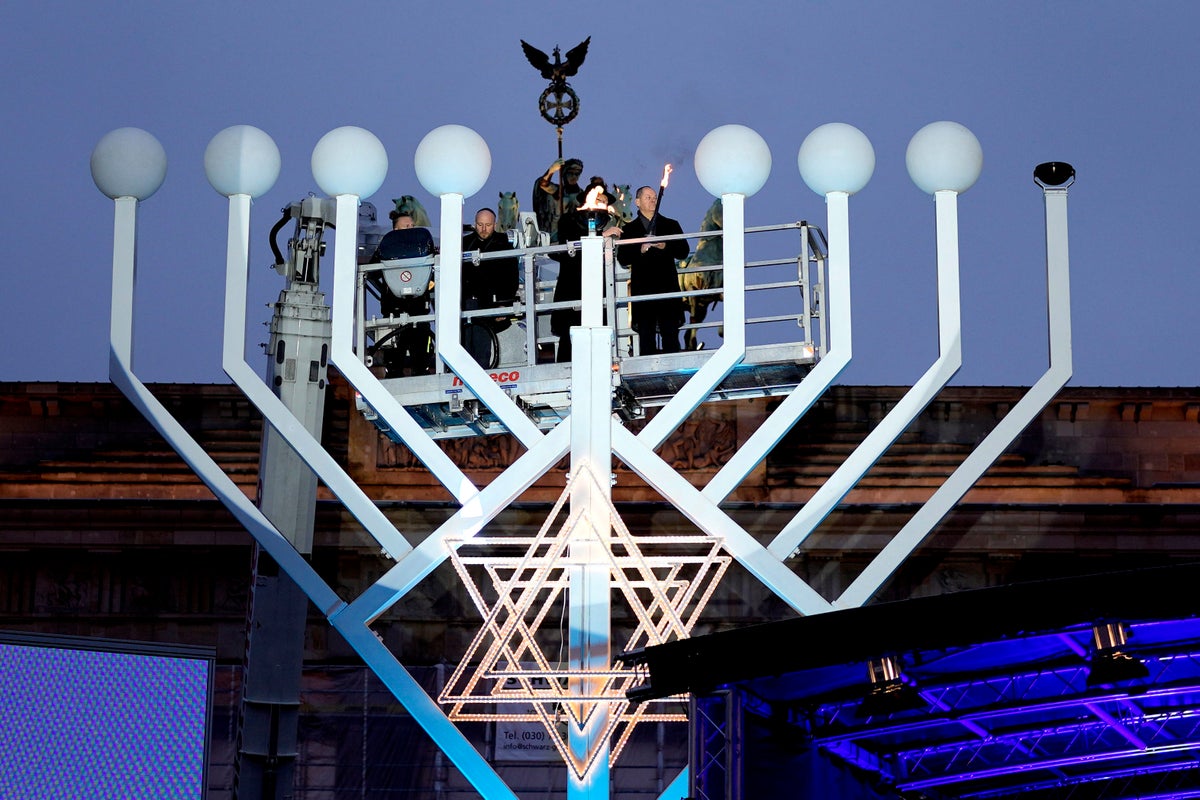 Germany's chancellor lights first Hanukkah candle on a huge menorah at Berlin's Brandenburg Gate