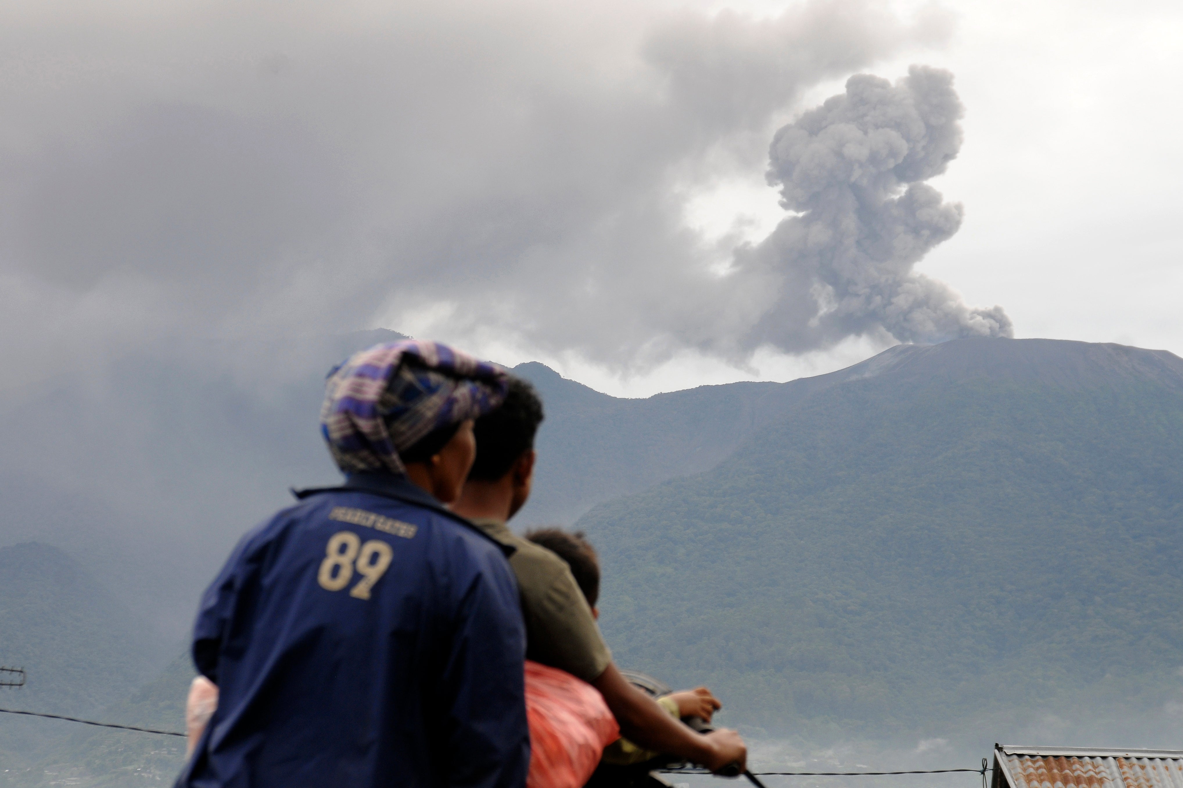 Motorists ride past by as Mount Marapi spews volcanic materials during its eruption in Agam, West Sumatra, Indonesia