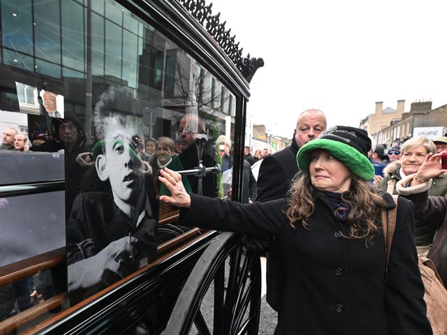 <p>Mourners touch the glass window of the carriage as the funeral procession of Shane MacGowan takes place in Dublin</p>