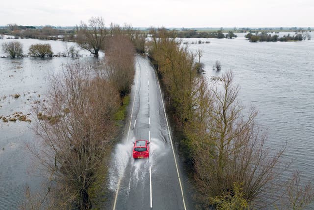 <p>Cars make their way through surface water on the A1101 in Welney in Norfolk</p>