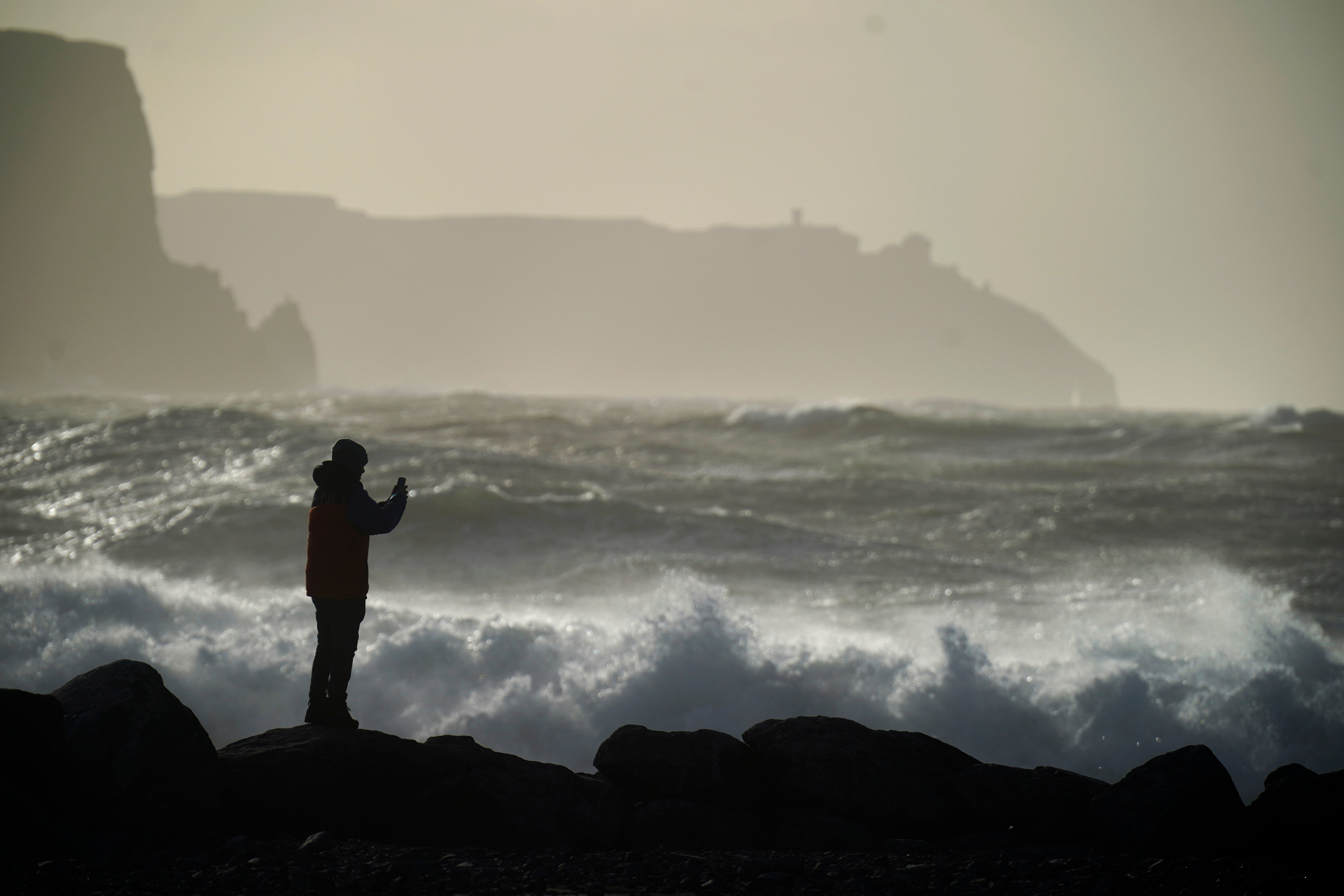 A person watching high waves in Doolin in County Clare on the west coast of Ireland