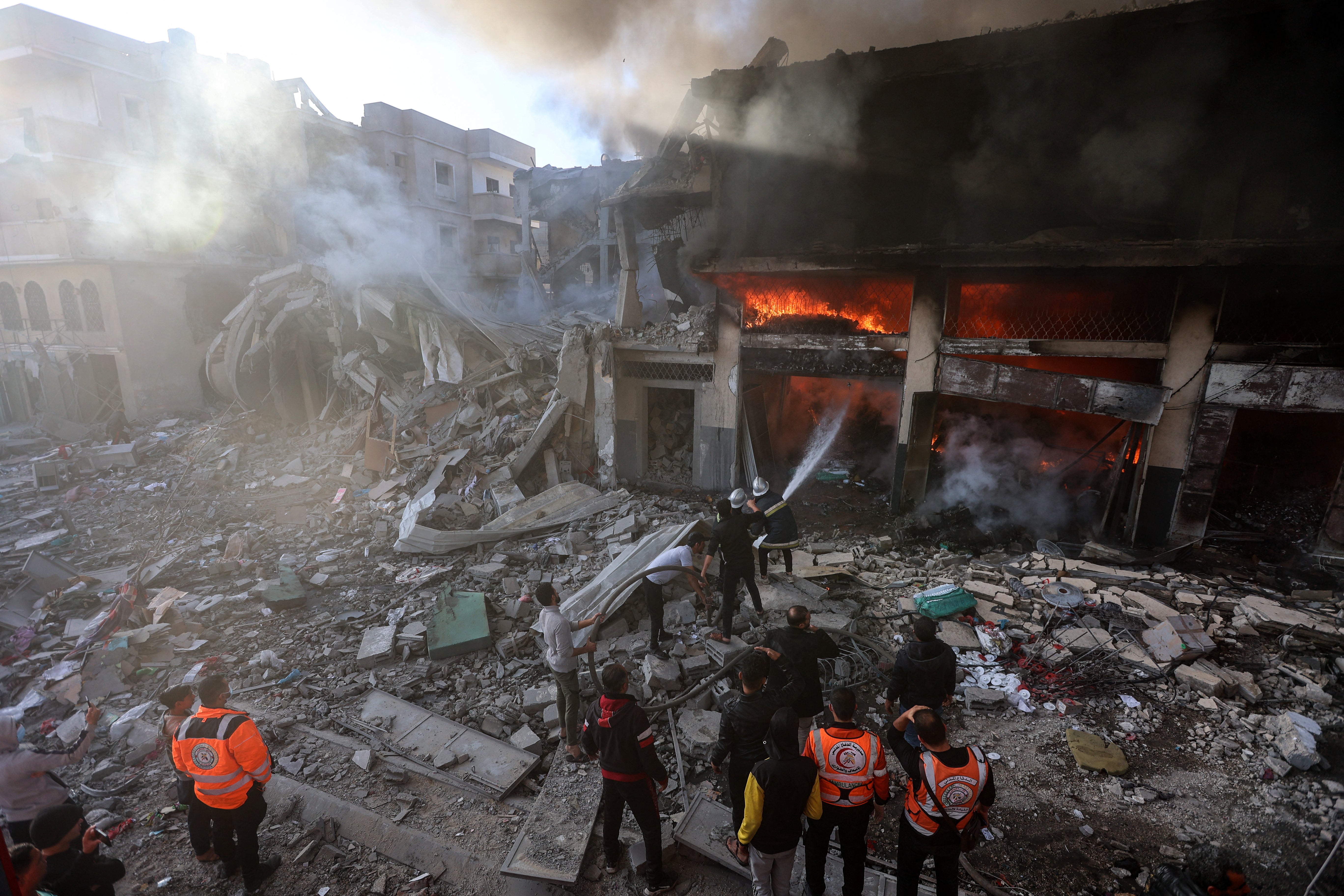 Firefights battle flames in a building hit by an Israeli strike in Khan Yunis in the southern Gaza Strip on December 9, 2023.