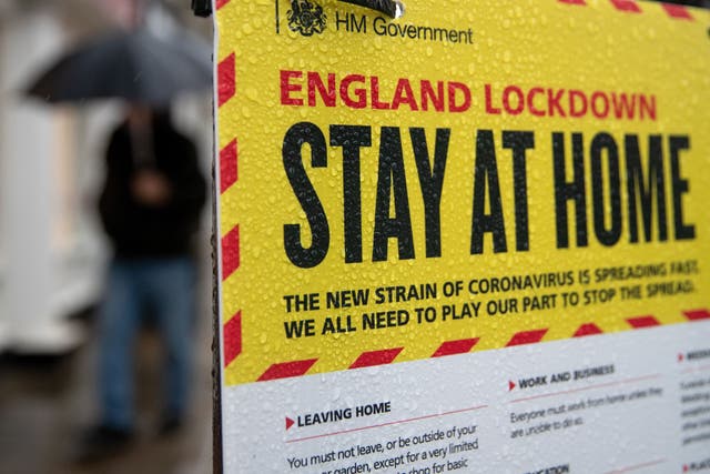 People walking past a Government sign warning people to stay at home on the High street in Winchester, Hampshire (Andrew Matthews/PA)