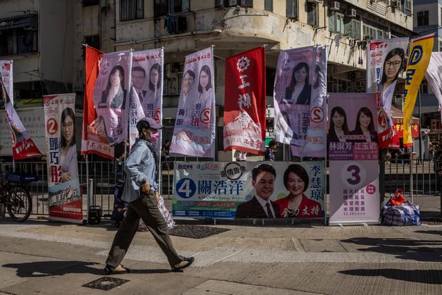 <p>A man walks past signs for candidates during the district council election in Hong Kong on 10 December 2023</p>