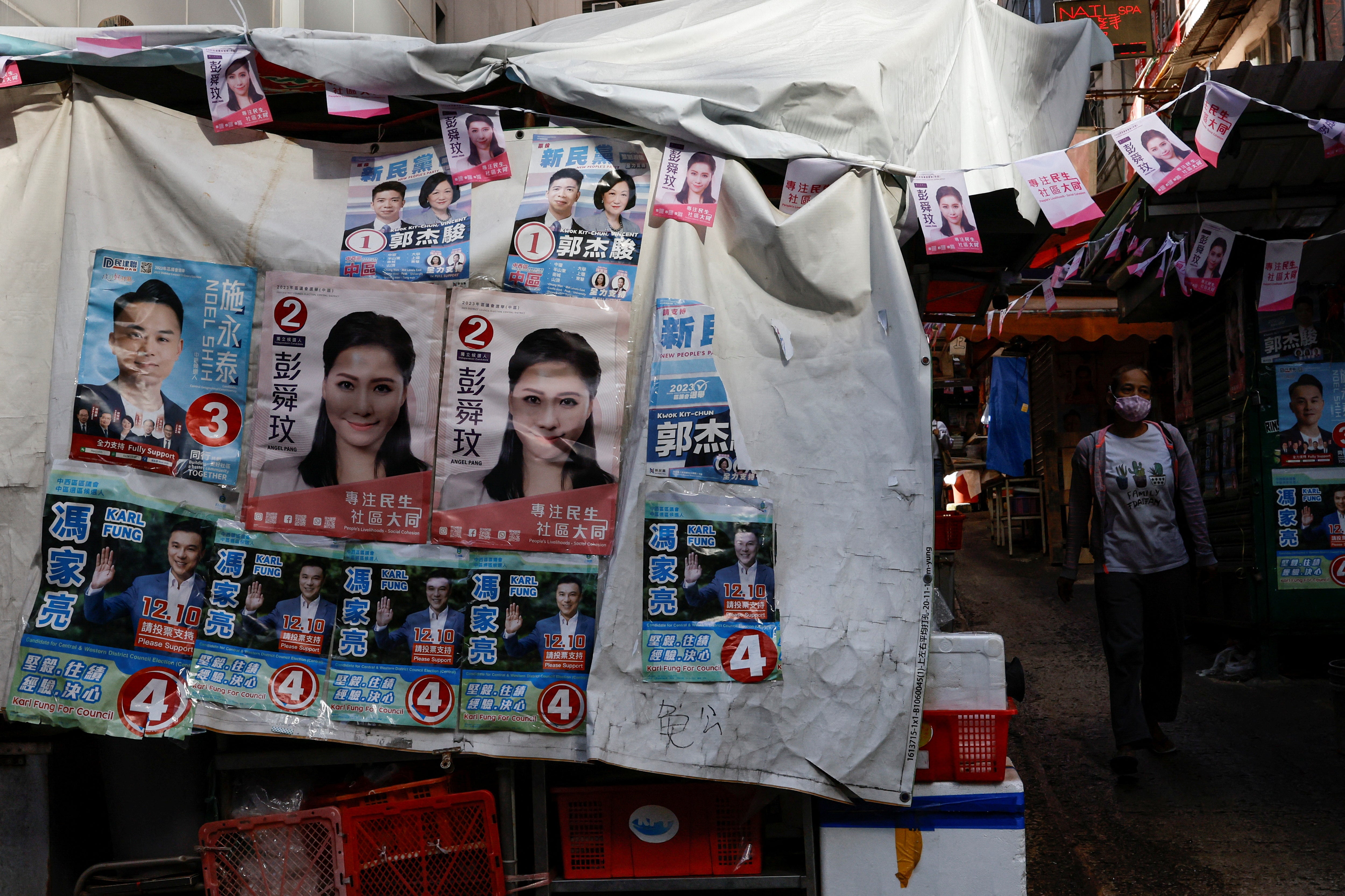 A woman walks past a stall with campaign posters of the District Council election candidates, in Hong Kong