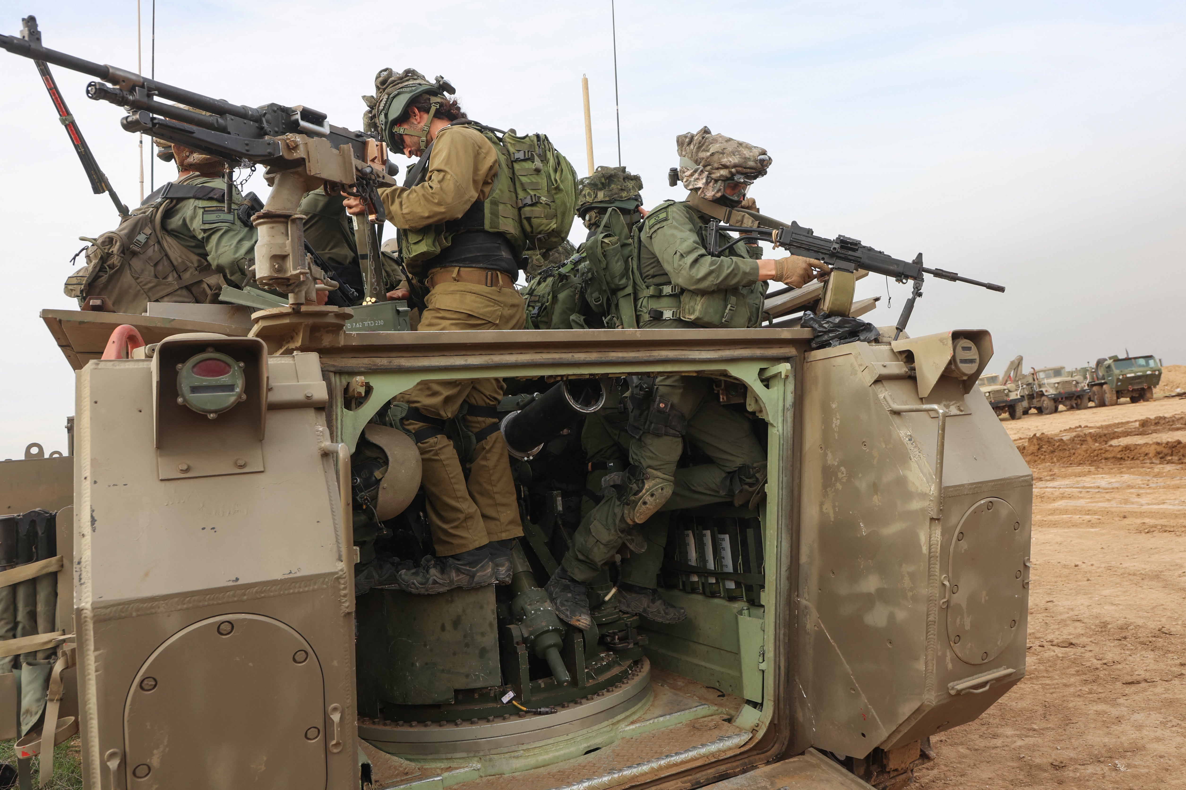 Israeli troops prepare weapons by the border fence before entering the Gaza Strip on Sunday