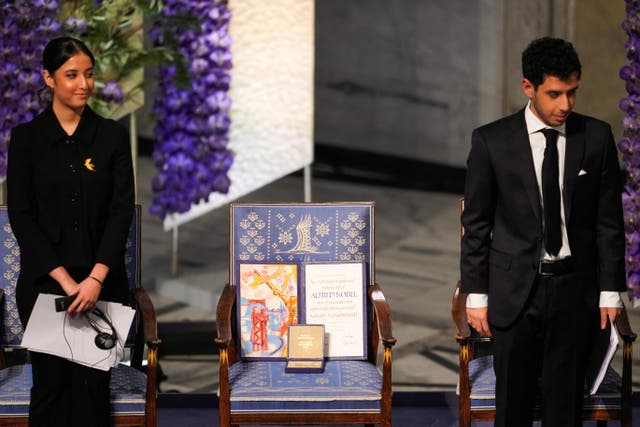 <p>Kiana and Ali Rahmani, children of Narges Mohammadi at the ceremony in Oslo. The empty chair represents a space left for their mother</p>
