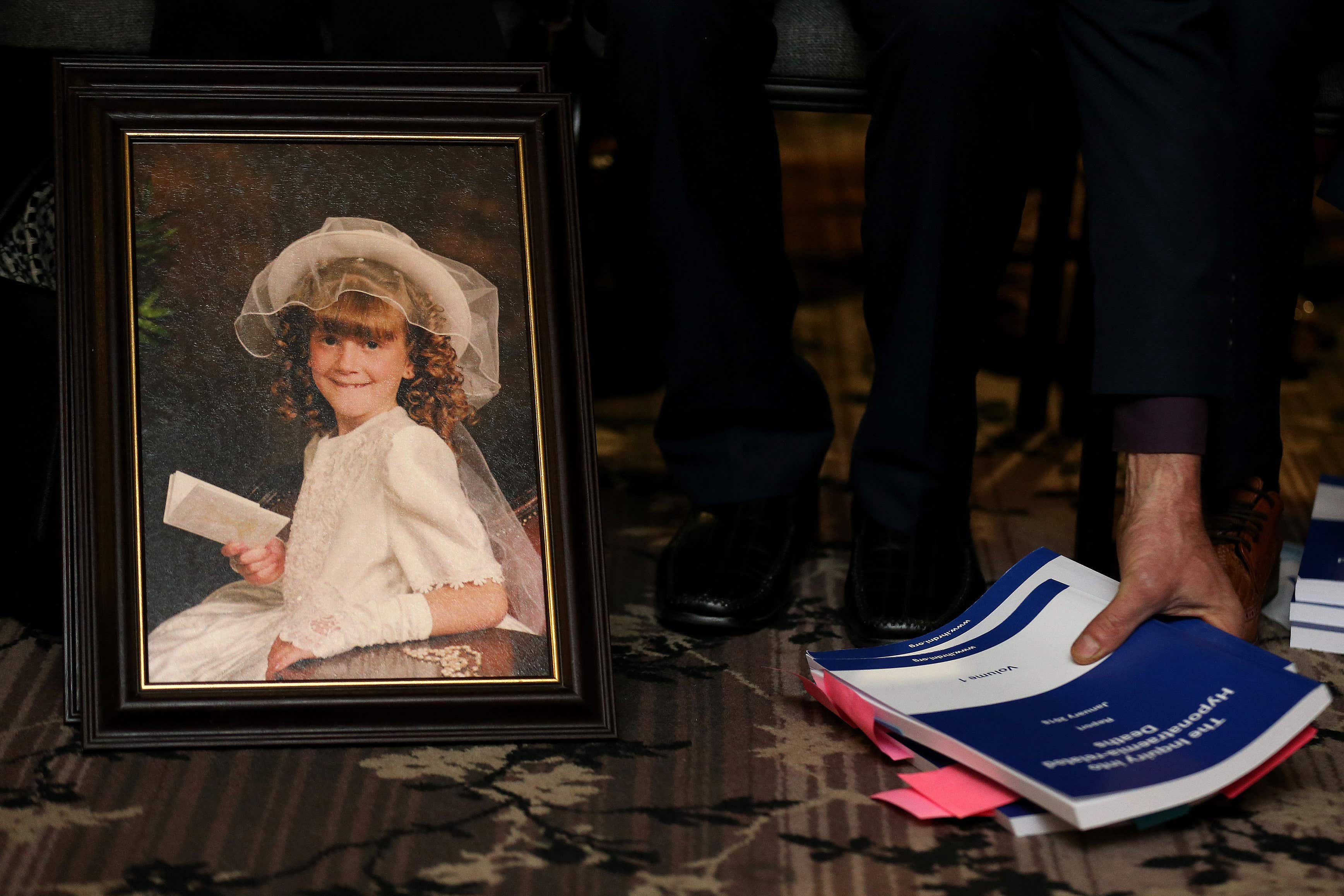 A photograph of Raychel Ferguson who died on 10 June 2001 sits alongside a copy of the findings of the hyponatraemia inquiry (Brian Lawless/PA)