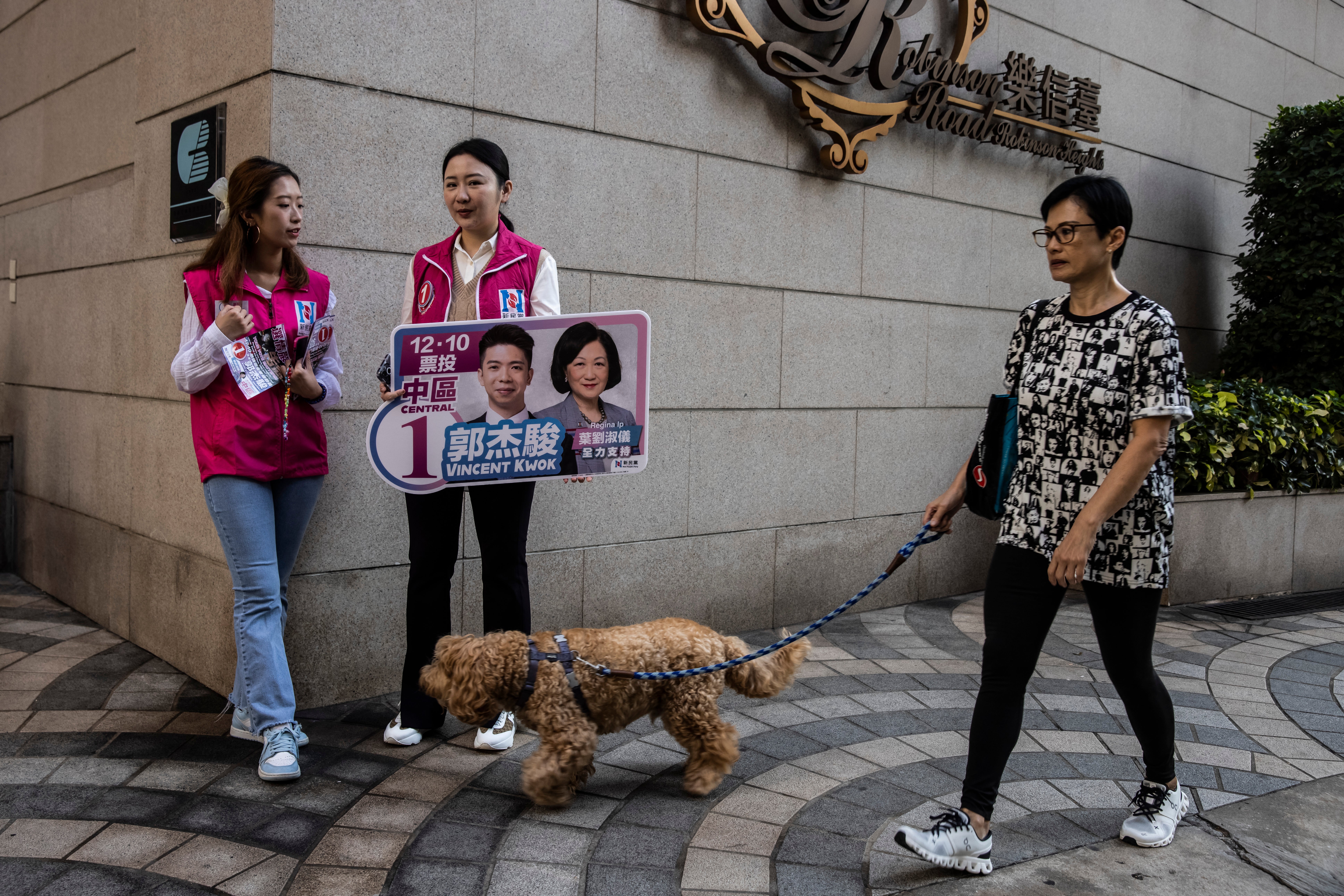 Two women hold a sign for a candidate near a polling station for district elections in Hong Kong on