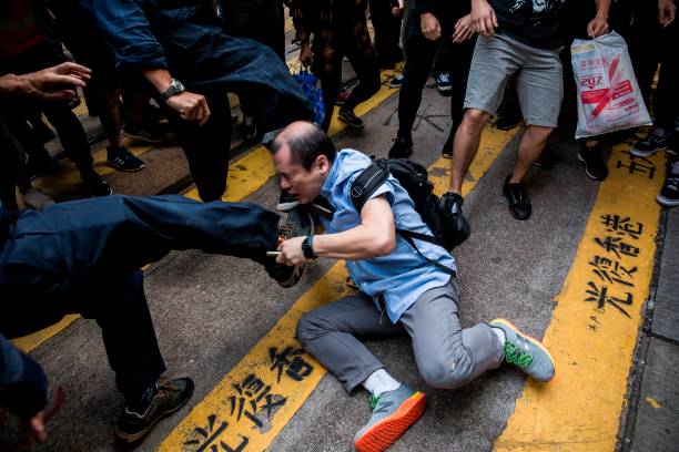 A man (C) is beaten after getting in an argument during a demonstration of office workers and protesters, in Central in Hong Kong during 2019 protests
