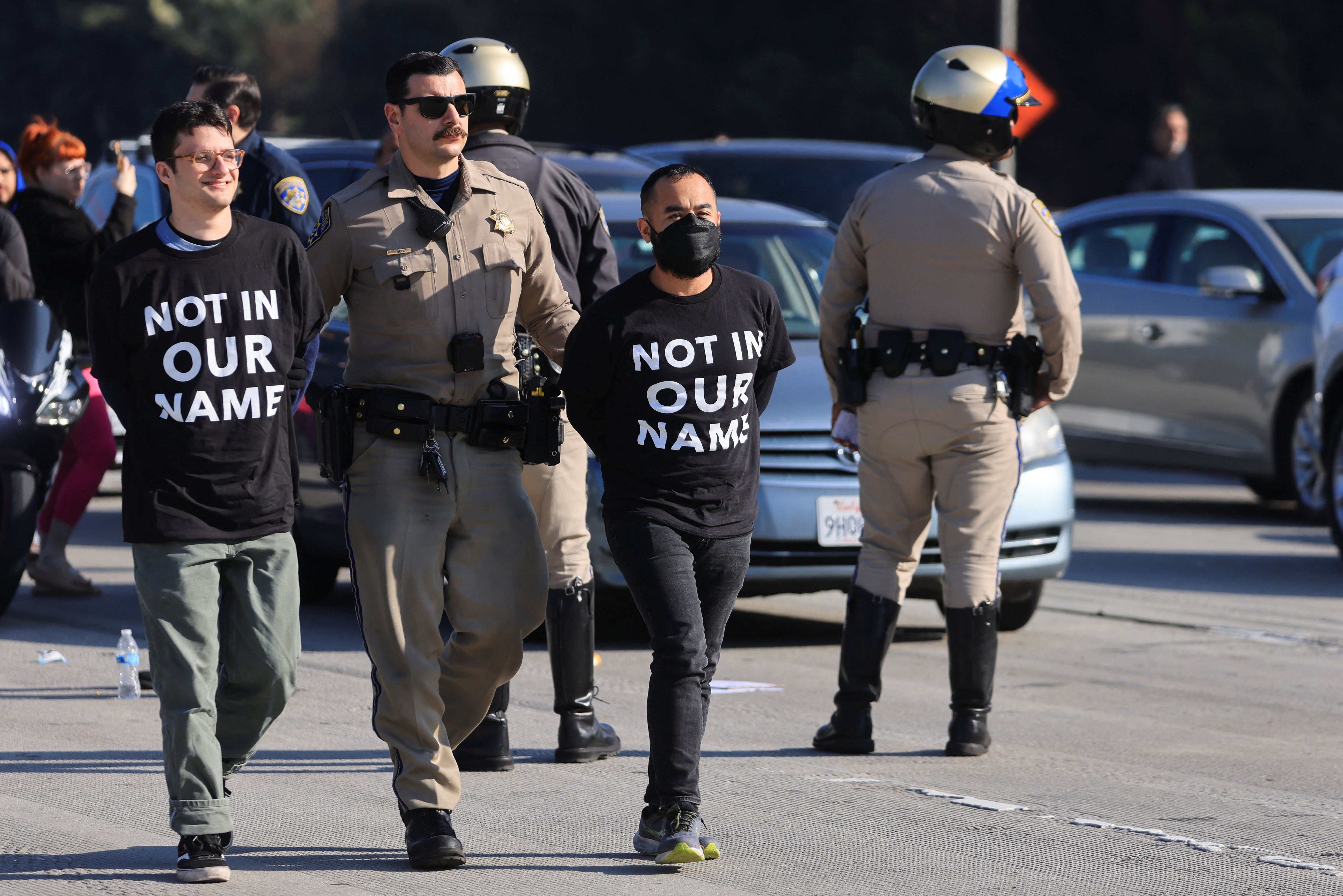 A law enforcement officer detains demonstrators during protest on 110 Freeway in Los Angeles