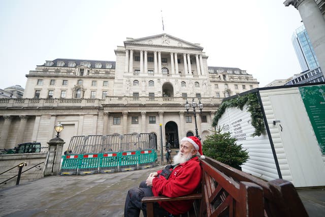<p>Gerard White, wearing a Santa hat and waiting for his wife to finish work, sitting outside the Bank of England in London</p>