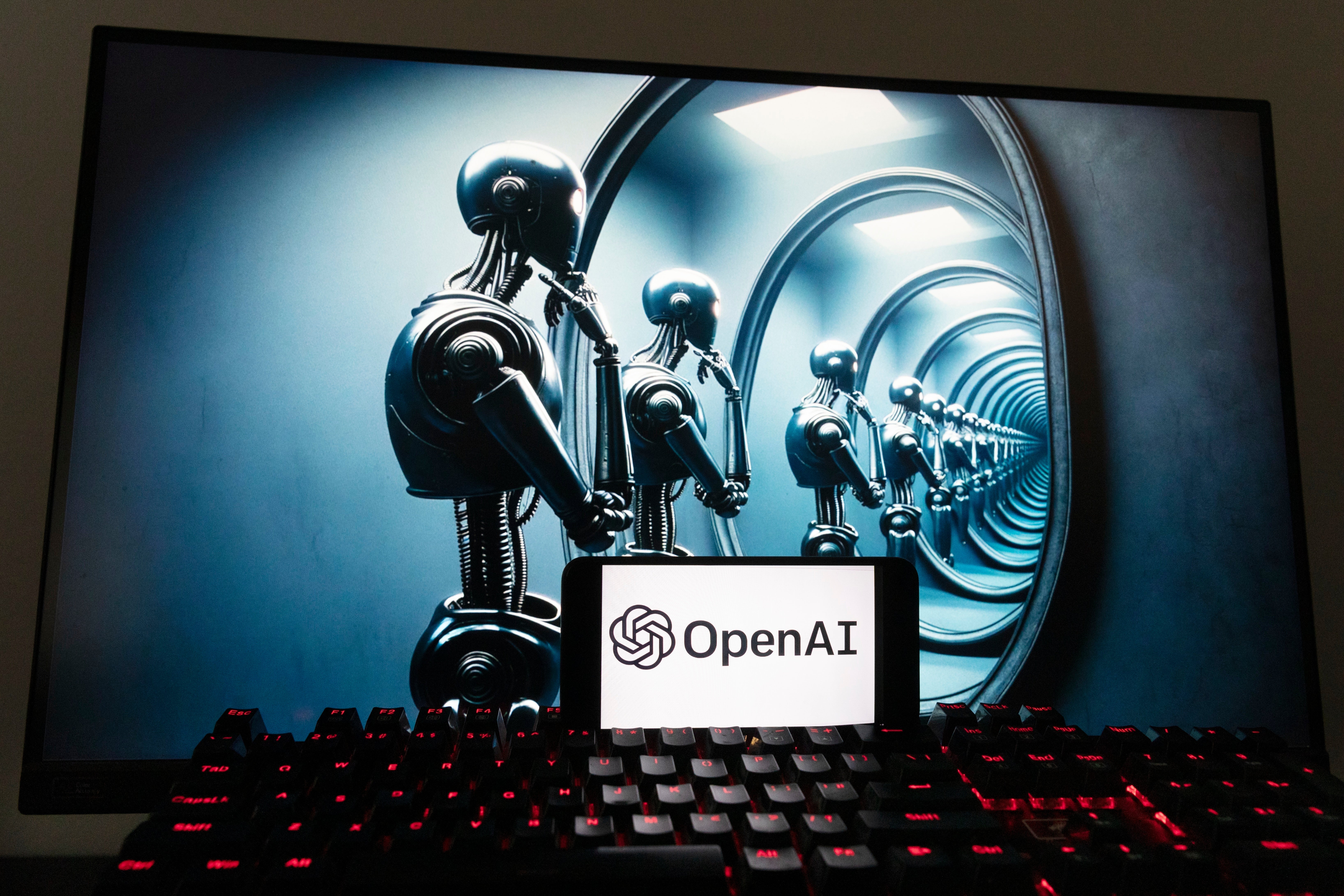 The OpenAI logo is seen displayed on a cell phone with an image on a computer screen generated by ChatGPT's Dall-E text-to-image model