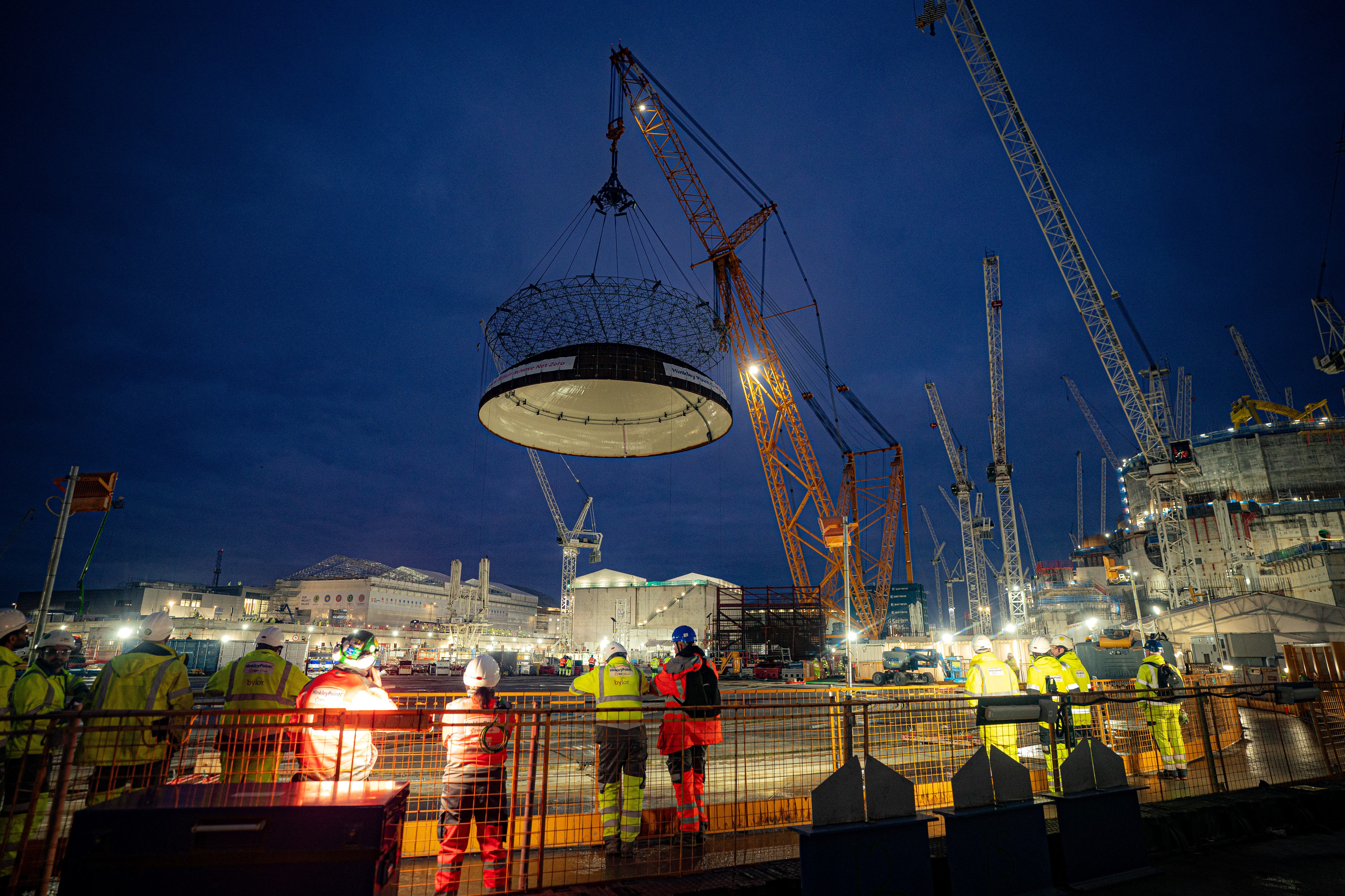 Engineering teams use the world’s largest crane – Big Carl – to lift a 245-tonne steel dome onto Hinkley Point C’s first reactor building (Ben Birchall/PA)