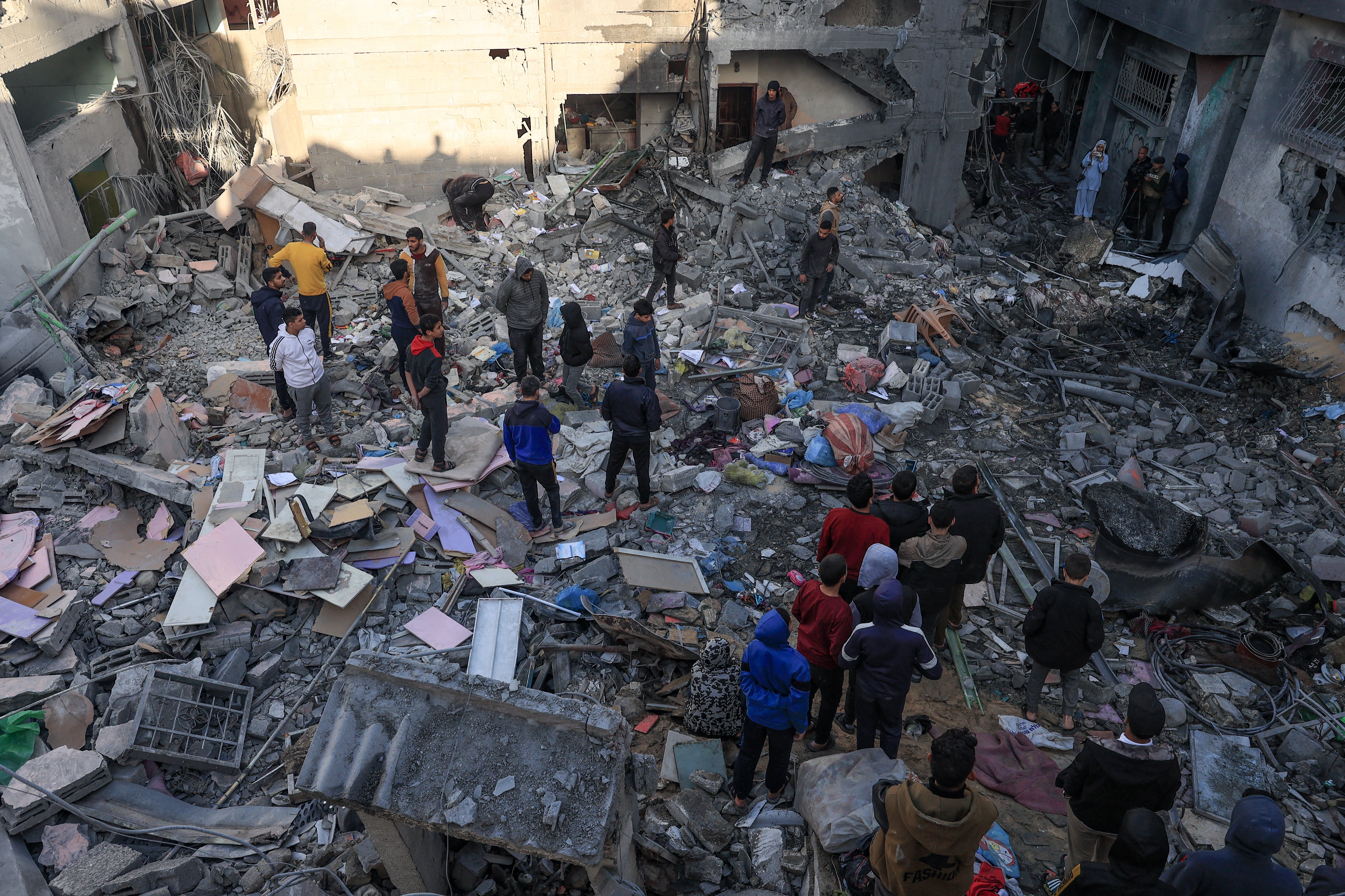 People gather amid the destruction following an early morning Israeli strike in Rafah in the southern Gaza Strip in December