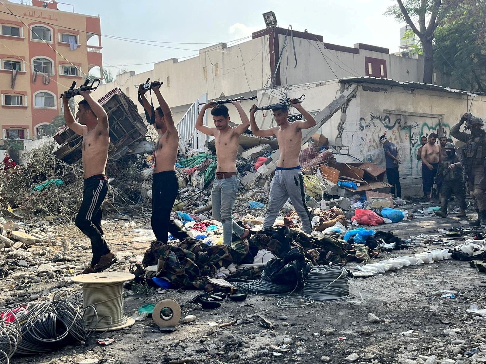 Men holding raised weapons are led out by Israeli soldiers near Kamal Adwan hospital in Jabalia, in the northern Gaza Strip
