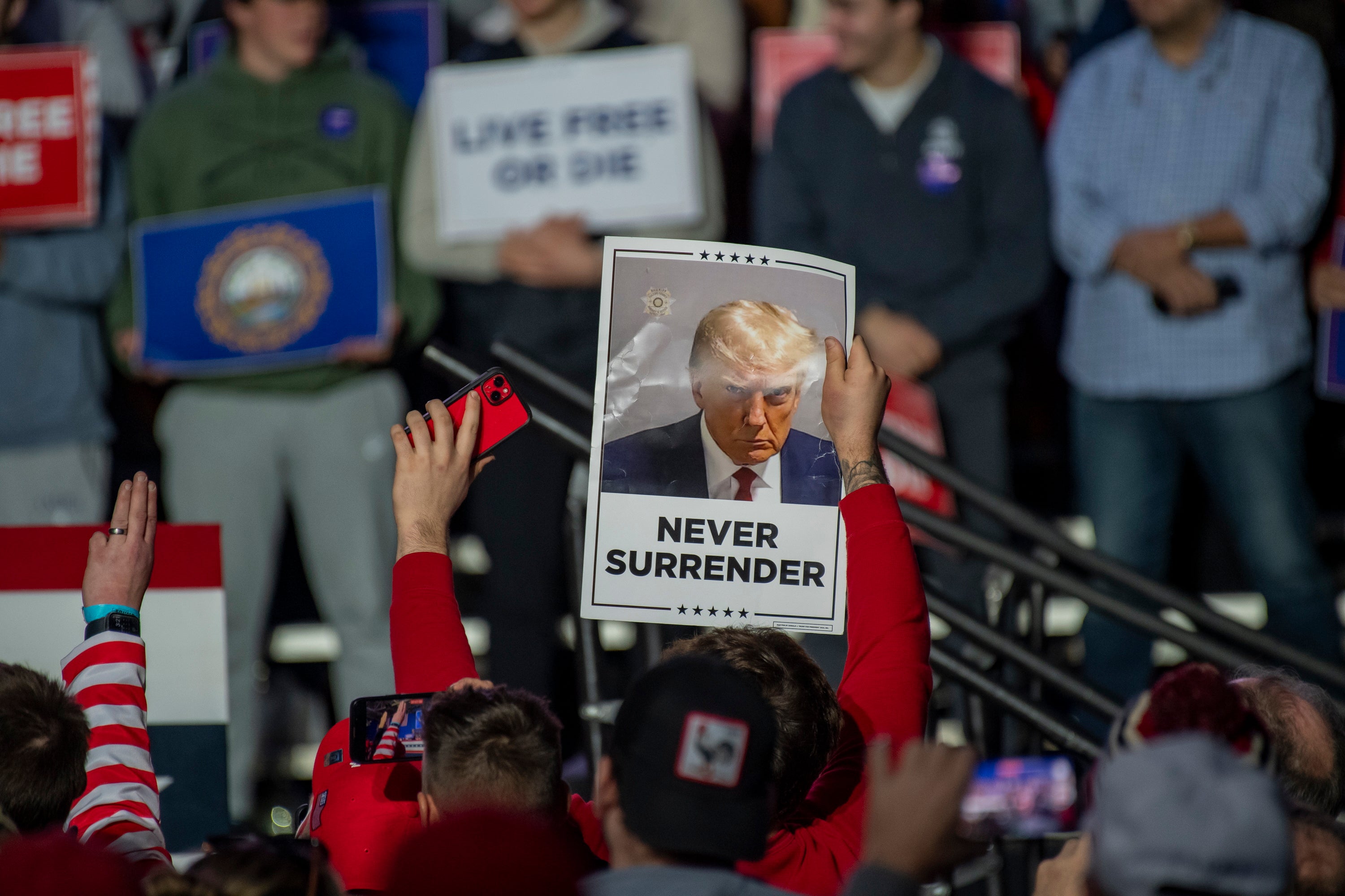 Donald Trump’s supporters in New Hampshire on 16 December hold a picture of his mugshot from criminal charges in Atlanta for an alleged scheme to overturn 2020 election results.