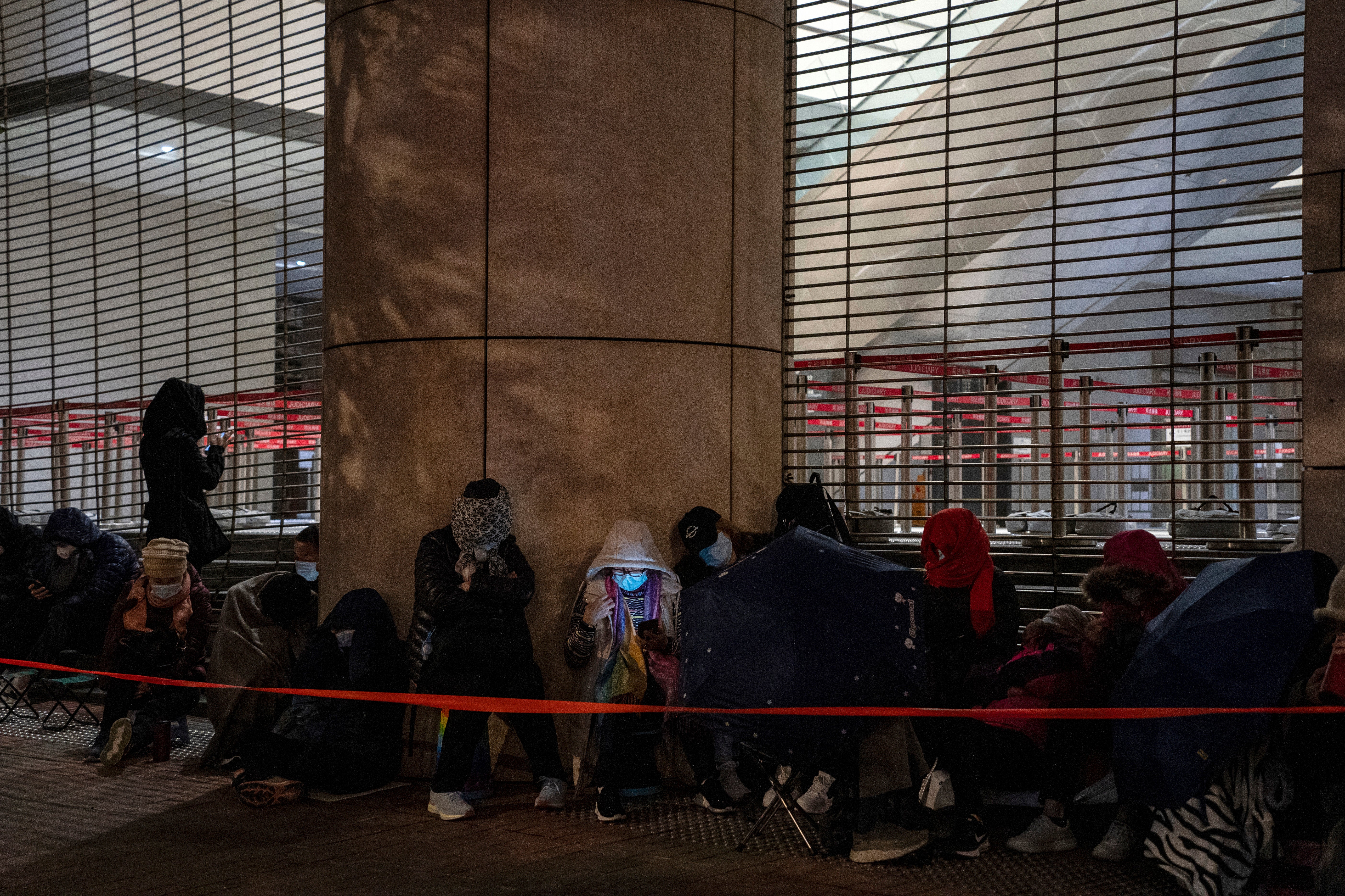 People wait behind a police line set up outside West Kowloon Magistrates' Courts