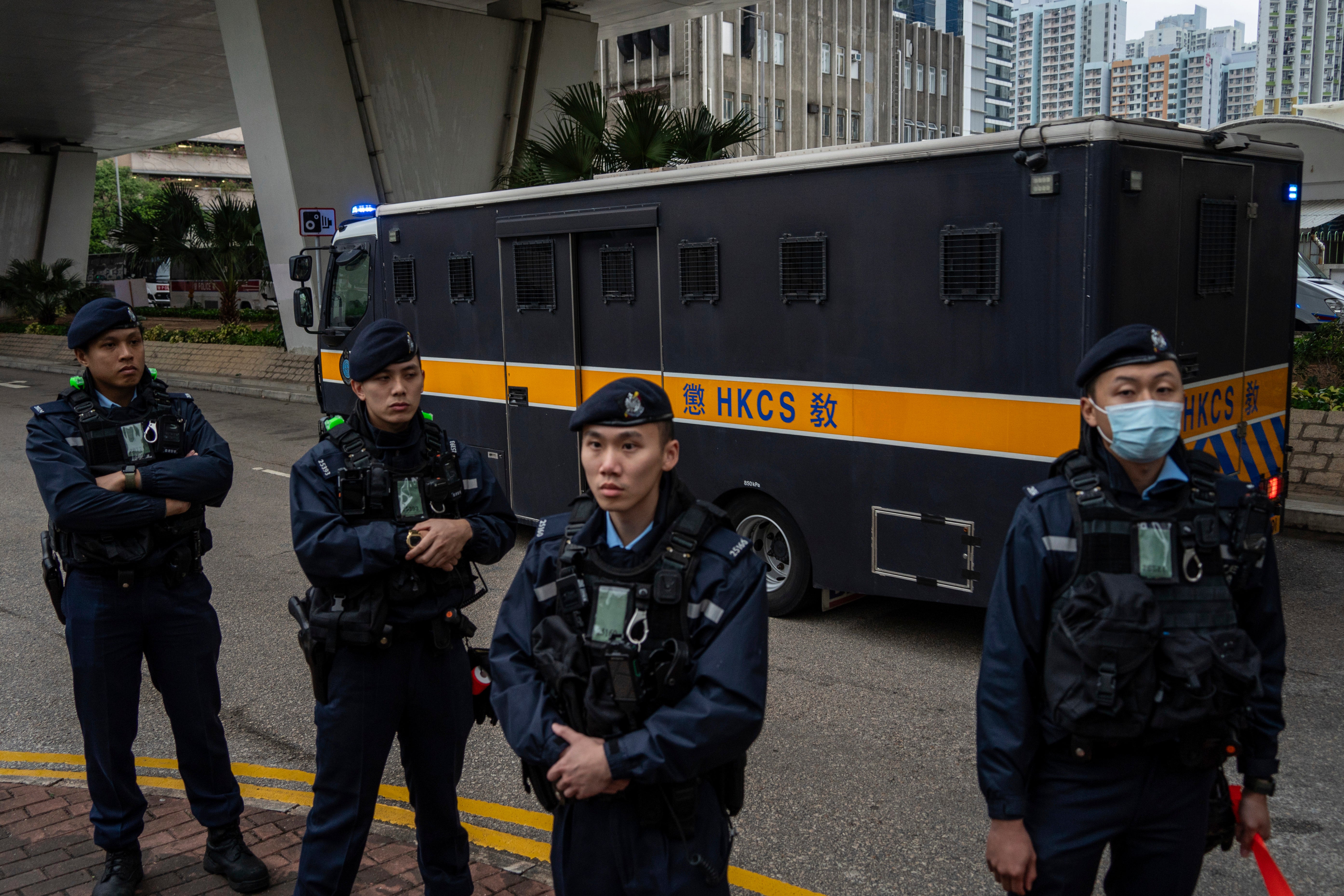 Police officers stand guard as an armored prison van carrying Jimmy Lai leaves West Kowloon Law Courts