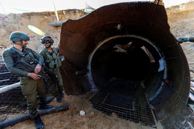 <p>Israeli soldiers chat near the opening to what Israel's military says is an iron-girded tunnel designed by Hamas</p>