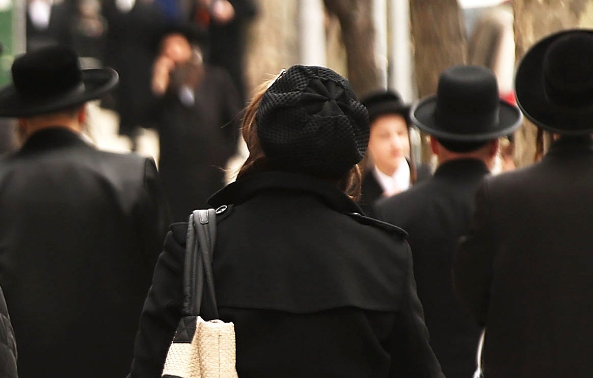 Hasidic men and women walk through a Jewish Orthodox neighborhood in Brooklyn on April 24, 2017 in New York City.