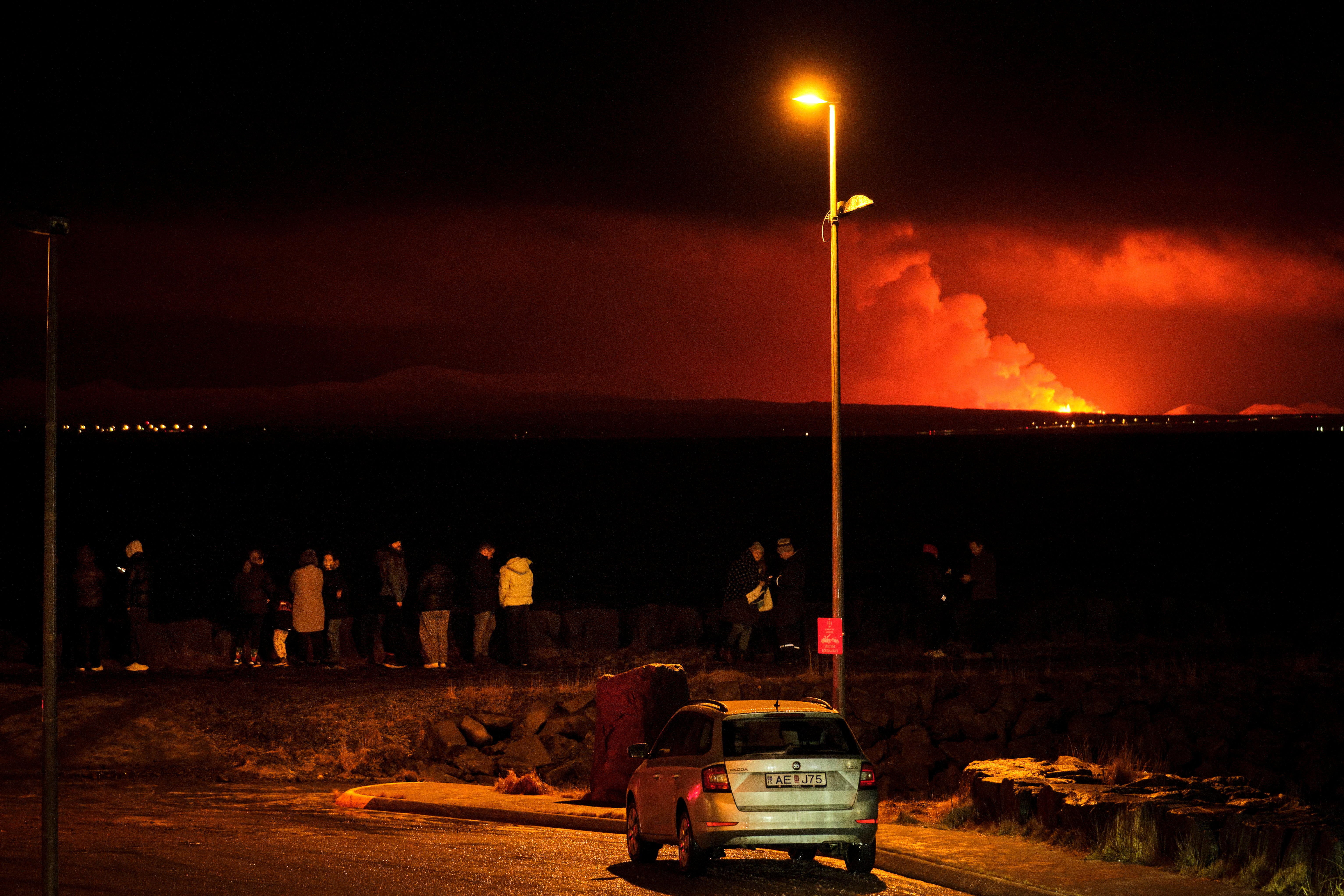 Thrill-seekers watch the gas plumes and lava from a distance in Iceland